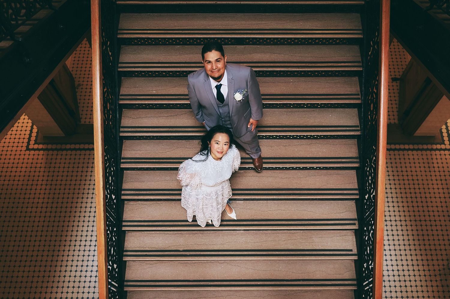 Wedding party members seated on industrial metal stairs for creative portrait.