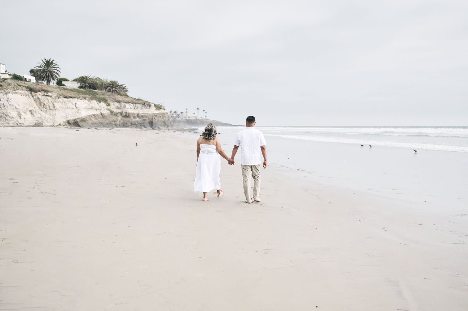 Wide angle beach landscape with figures walking along the shoreline.