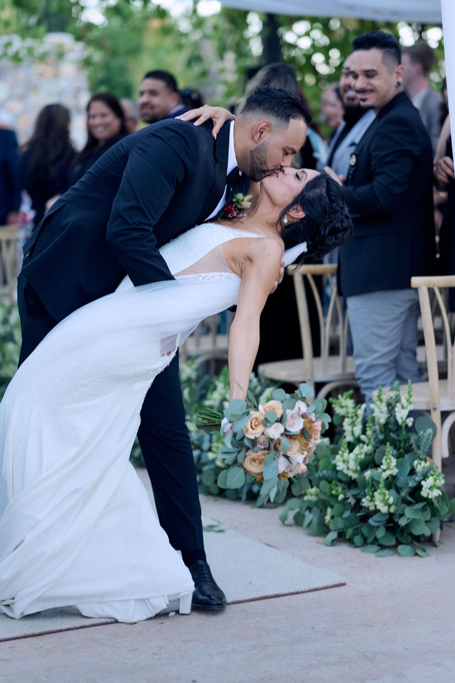 Wedding couple performs dramatic dip dance move during outdoor reception.