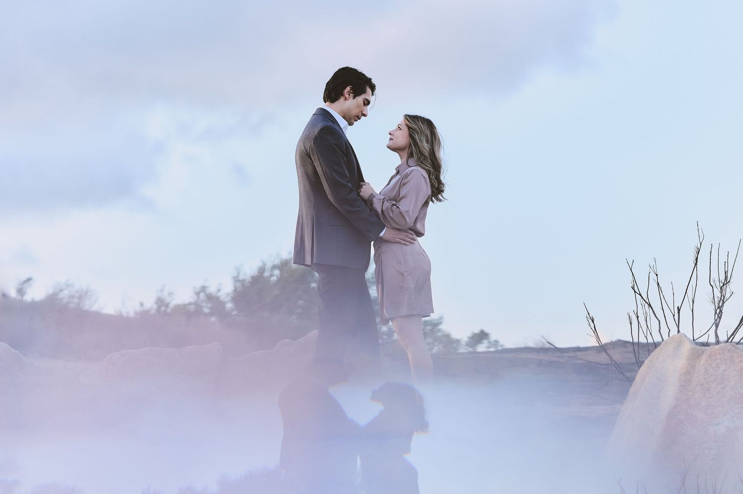 Romantic couple embracing in dreamy misty outdoor setting.