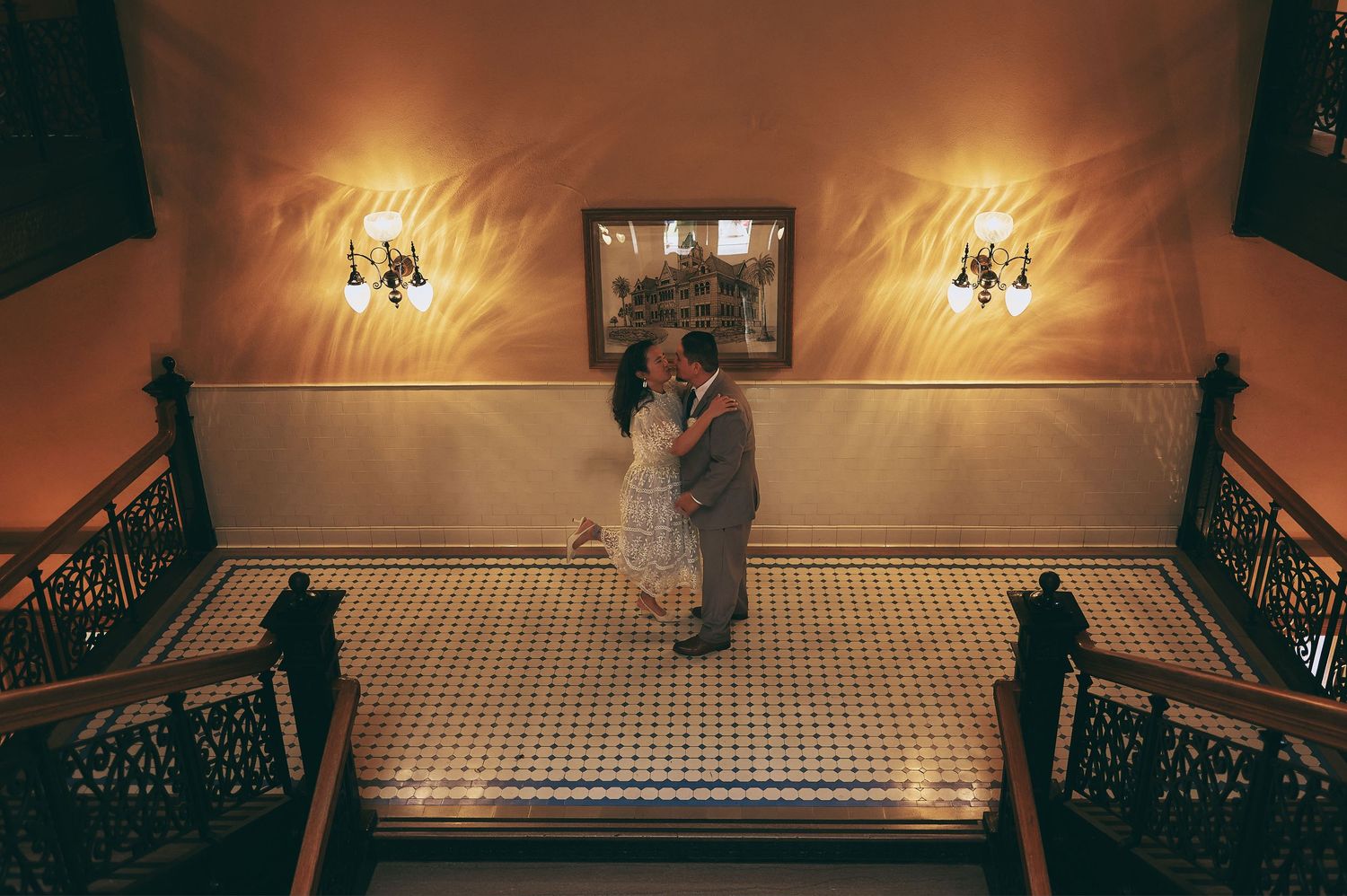 A dimly lit indoor venue with elegant chandeliers and architectural details.