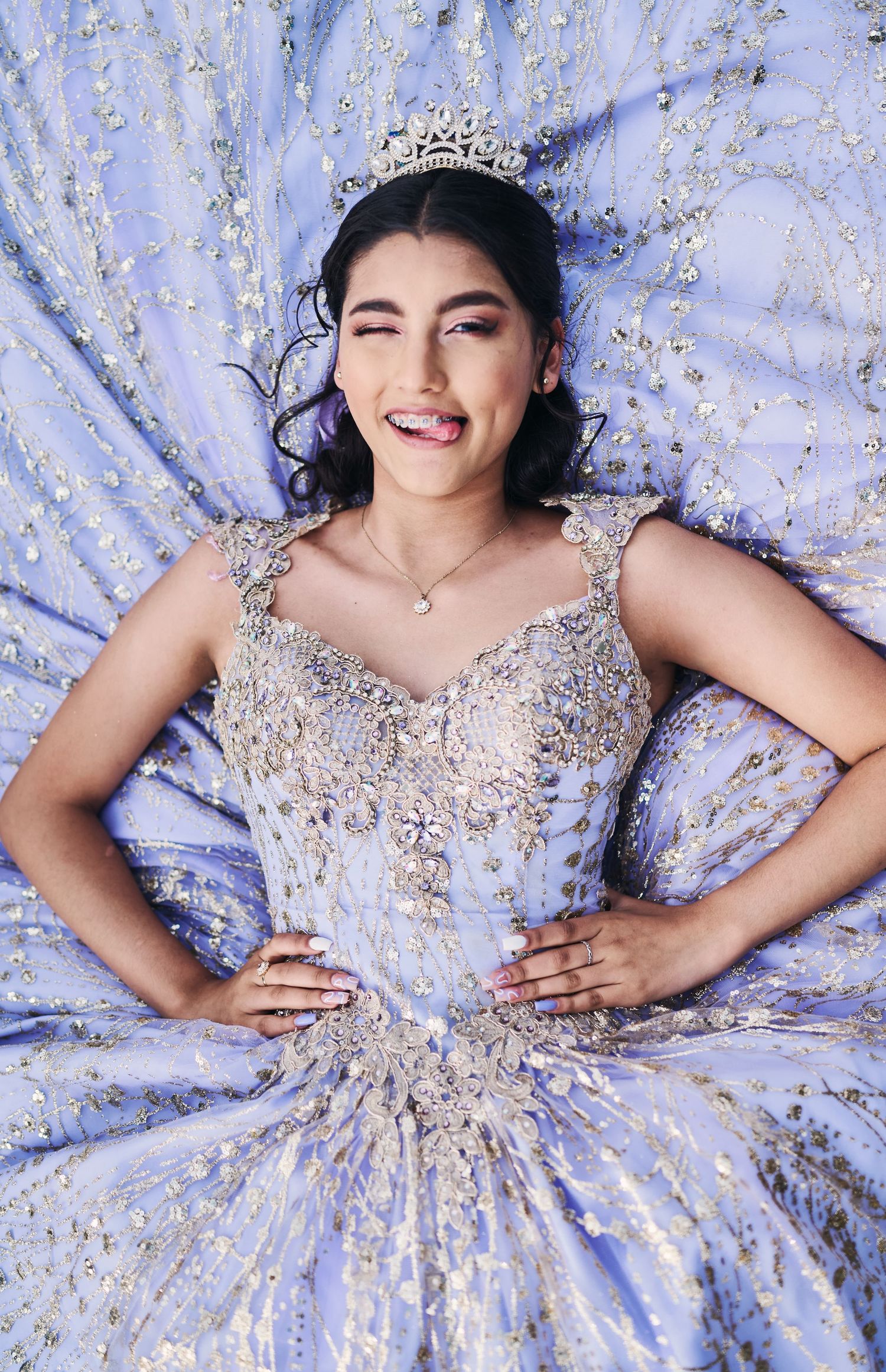 Elegant ball gown with intricate beading and sparkles photographed against a light purple backdrop.