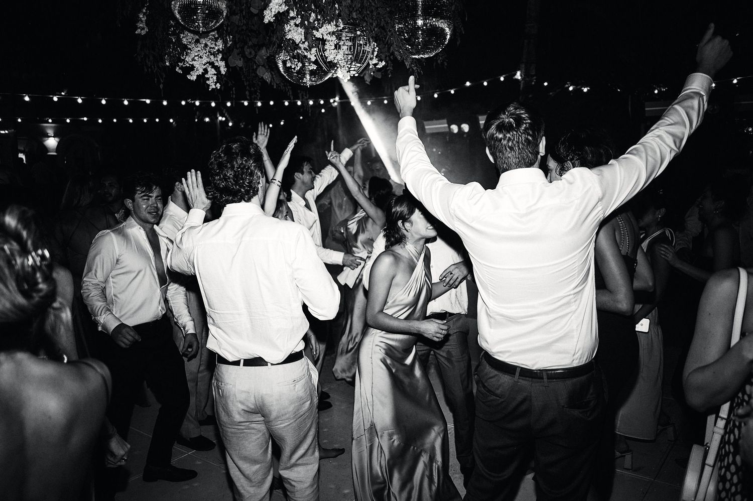 Dancers silhouetted against string lights at a nighttime celebration.