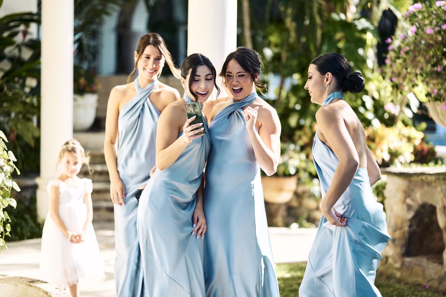 Bridesmaids in light blue dresses gather outdoors for a group photo.