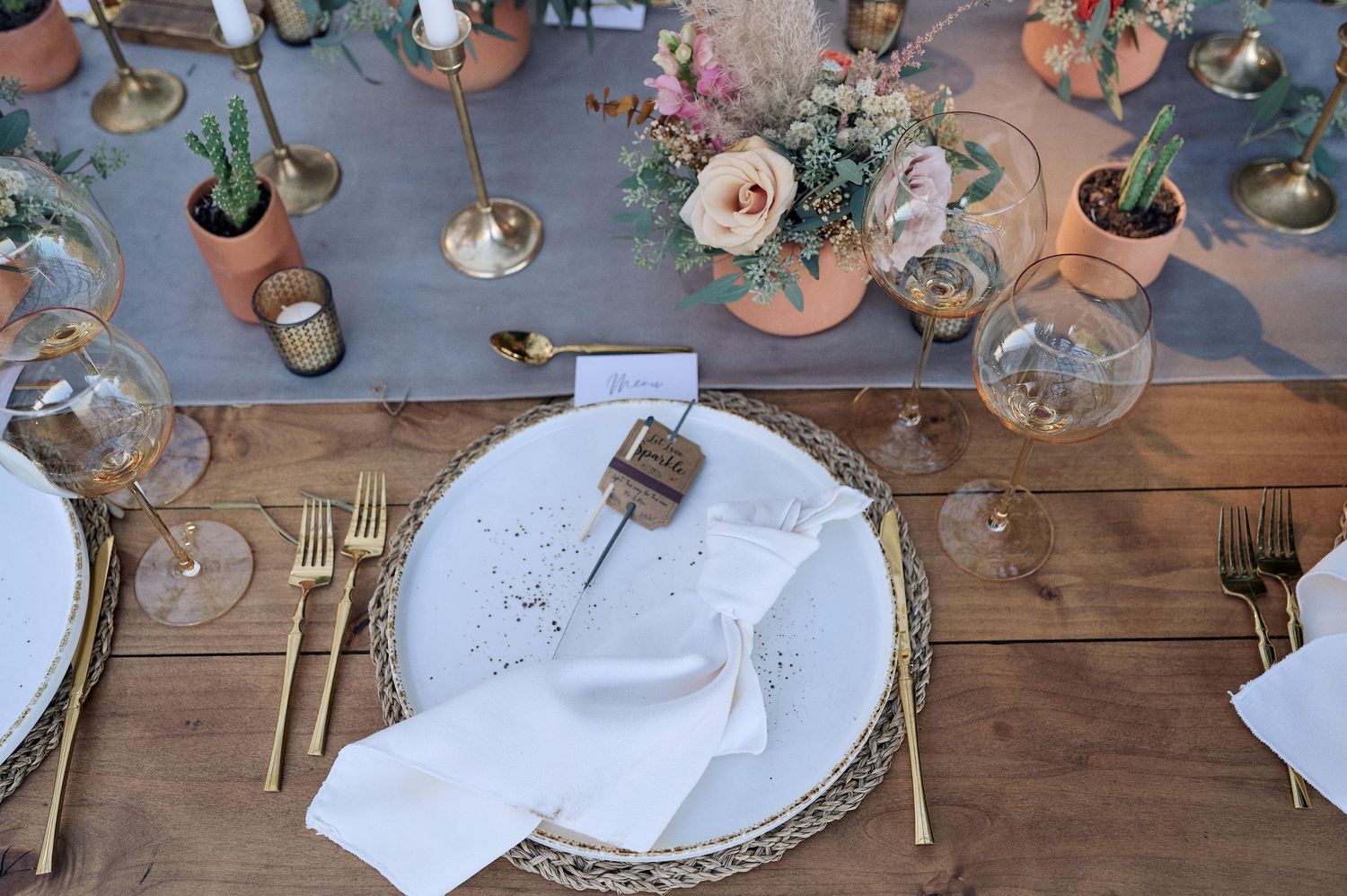 Elegant table settings with floral centerpieces and place cards on a rustic wooden surface.