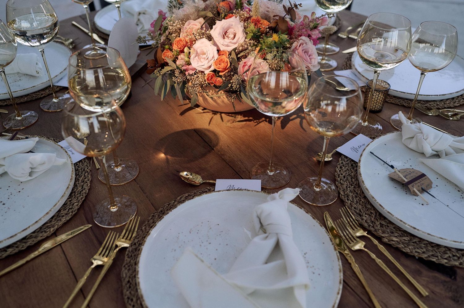 Luxurious wedding table decor with pink floral arrangements and fine china place settings.