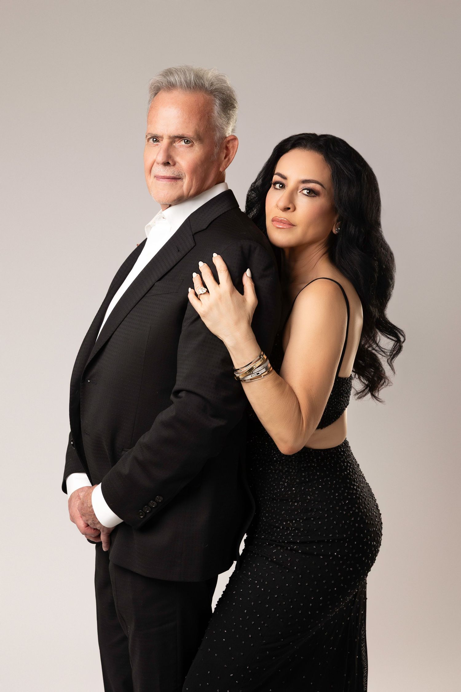 A formal studio portrait of two people in elegant black evening wear posed together.  Located in Palm Desert, California.