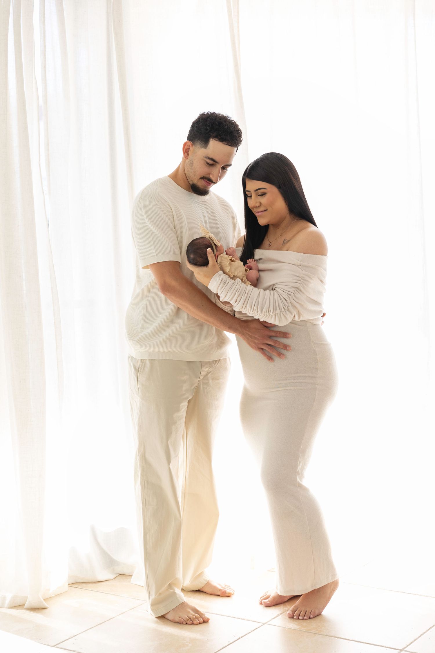 Sweet family maternity photos in white outfits by window with natural light.  Located in Palm Desert, California.