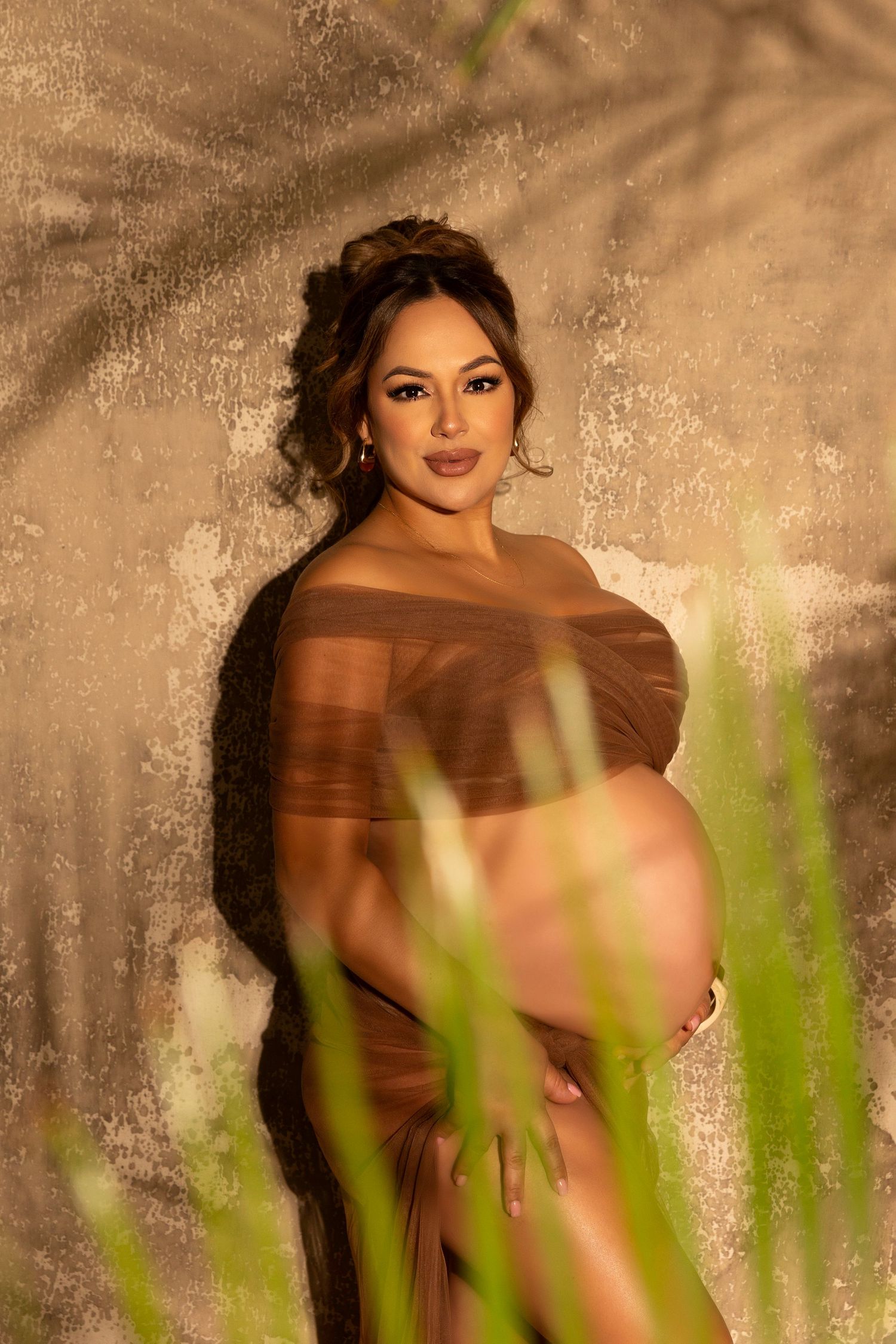 A warm-toned maternity portrait with natural light and plant shadows creating an ethereal effect.  Located in Palm Desert, California.