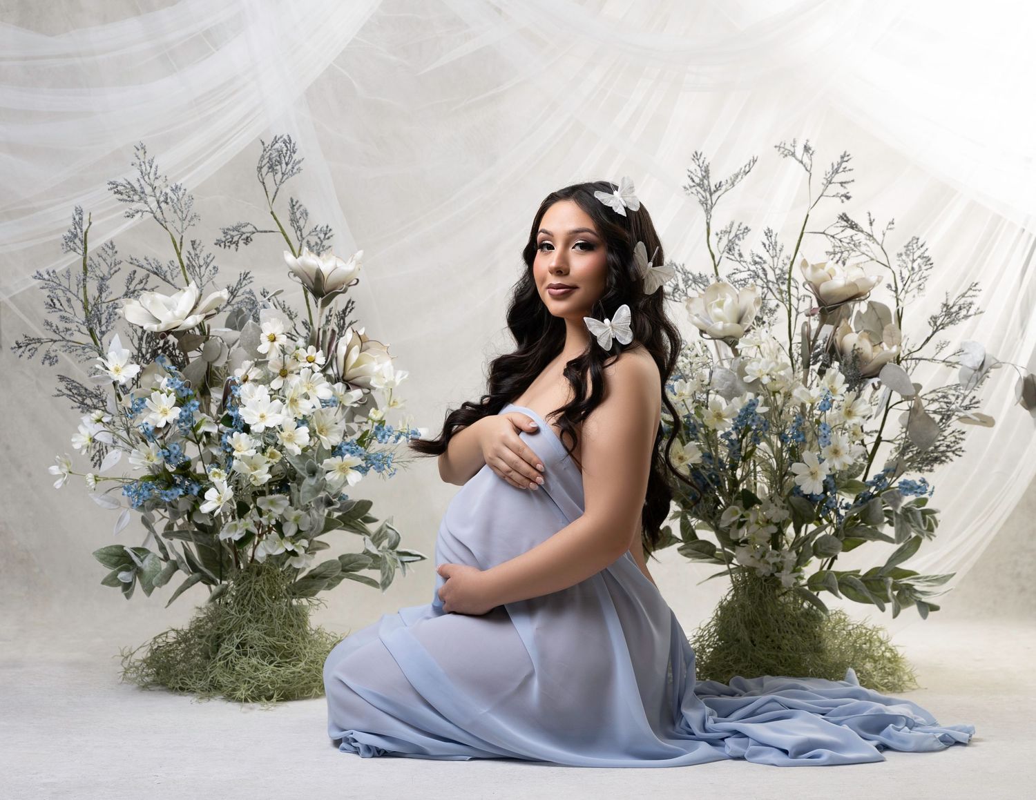 Ethereal maternity portrait with delicate flowers and flowing fabric in soft lighting.  Located in Palm Desert, California.