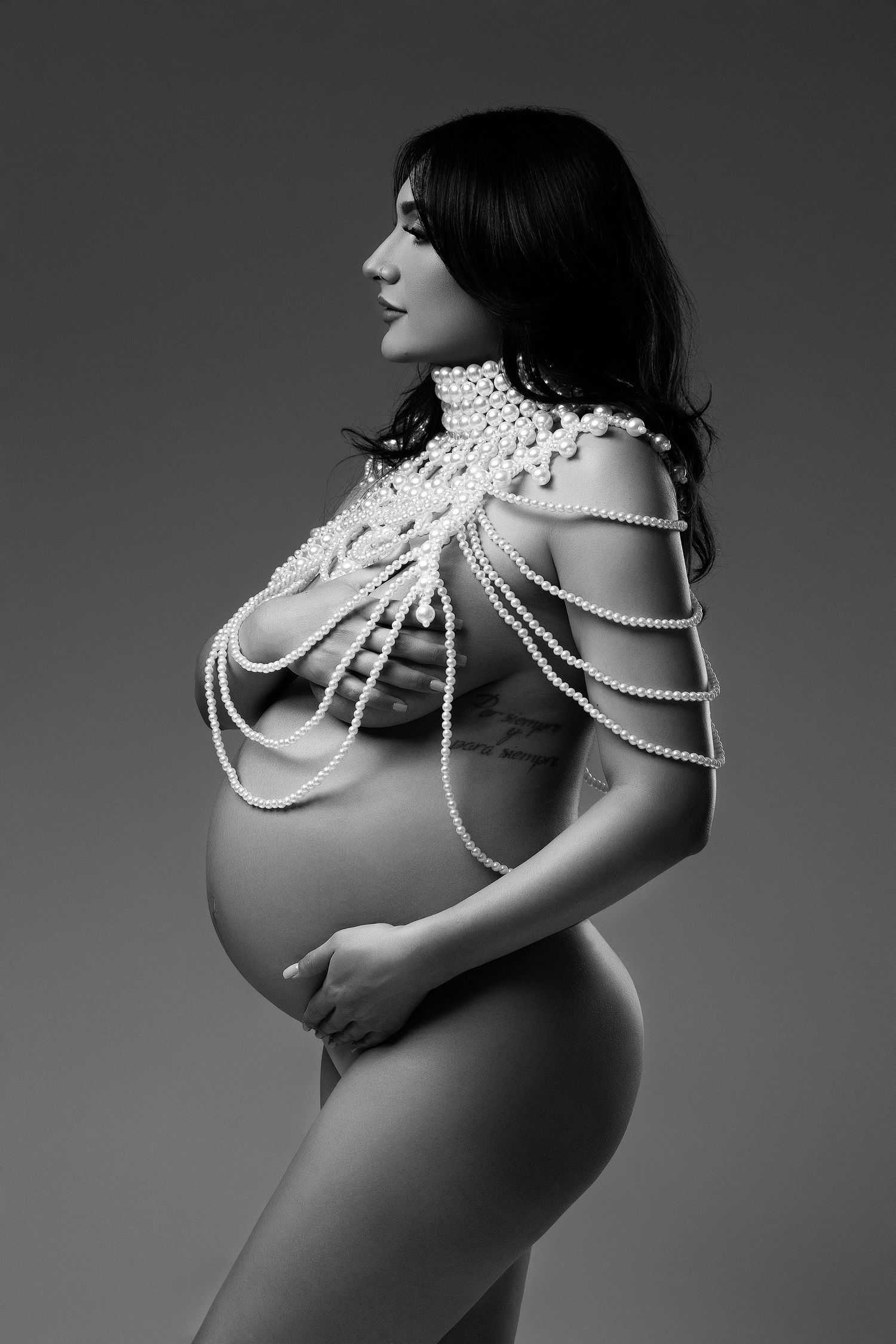 Black and white artistic portrait of a pregnant woman wearing pearl necklaces in multiple dramatic poses.