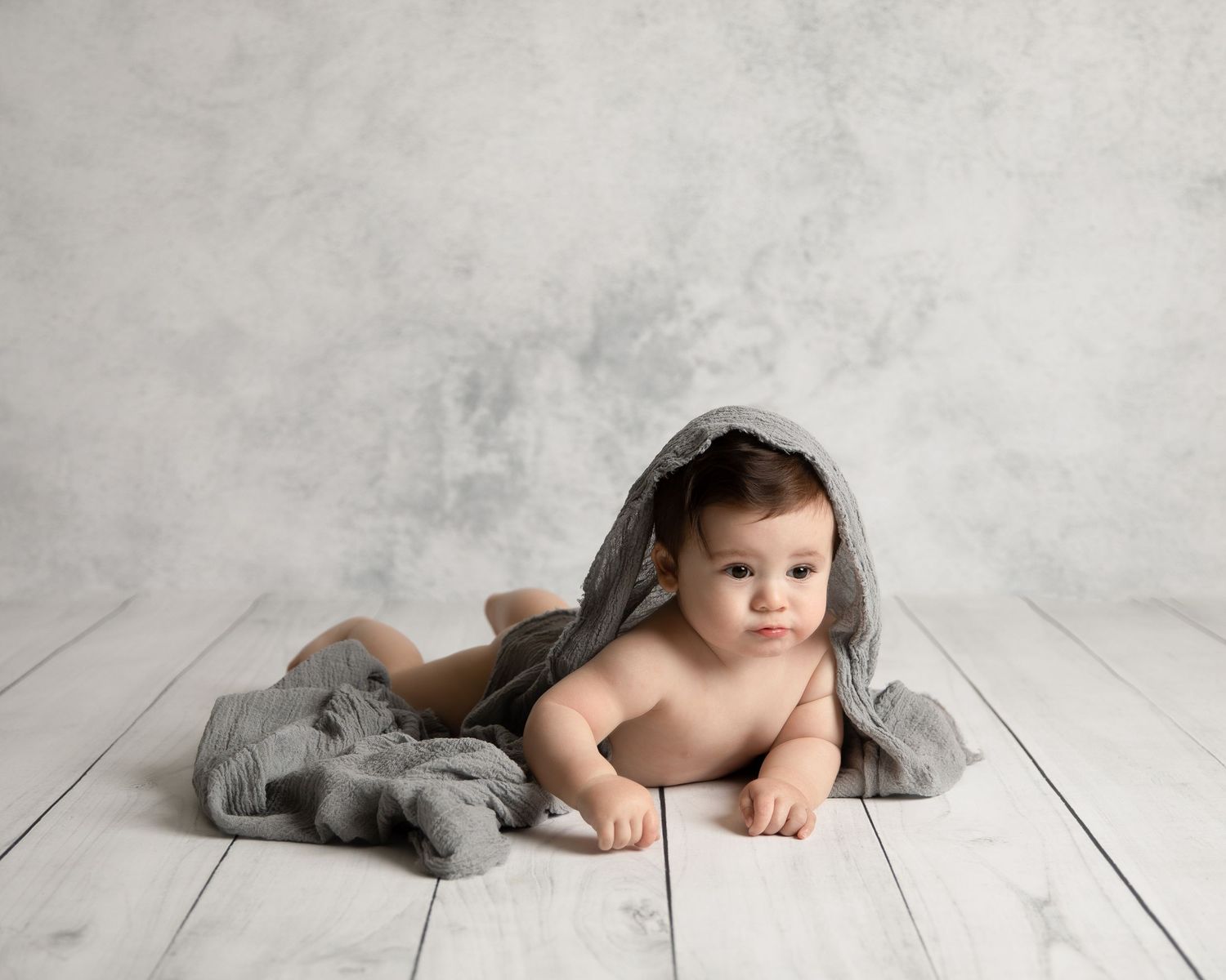 Artistic black and white portrait series with gray tulle fabric on white wooden floor of a small child.  Located in Palm Desert, California.