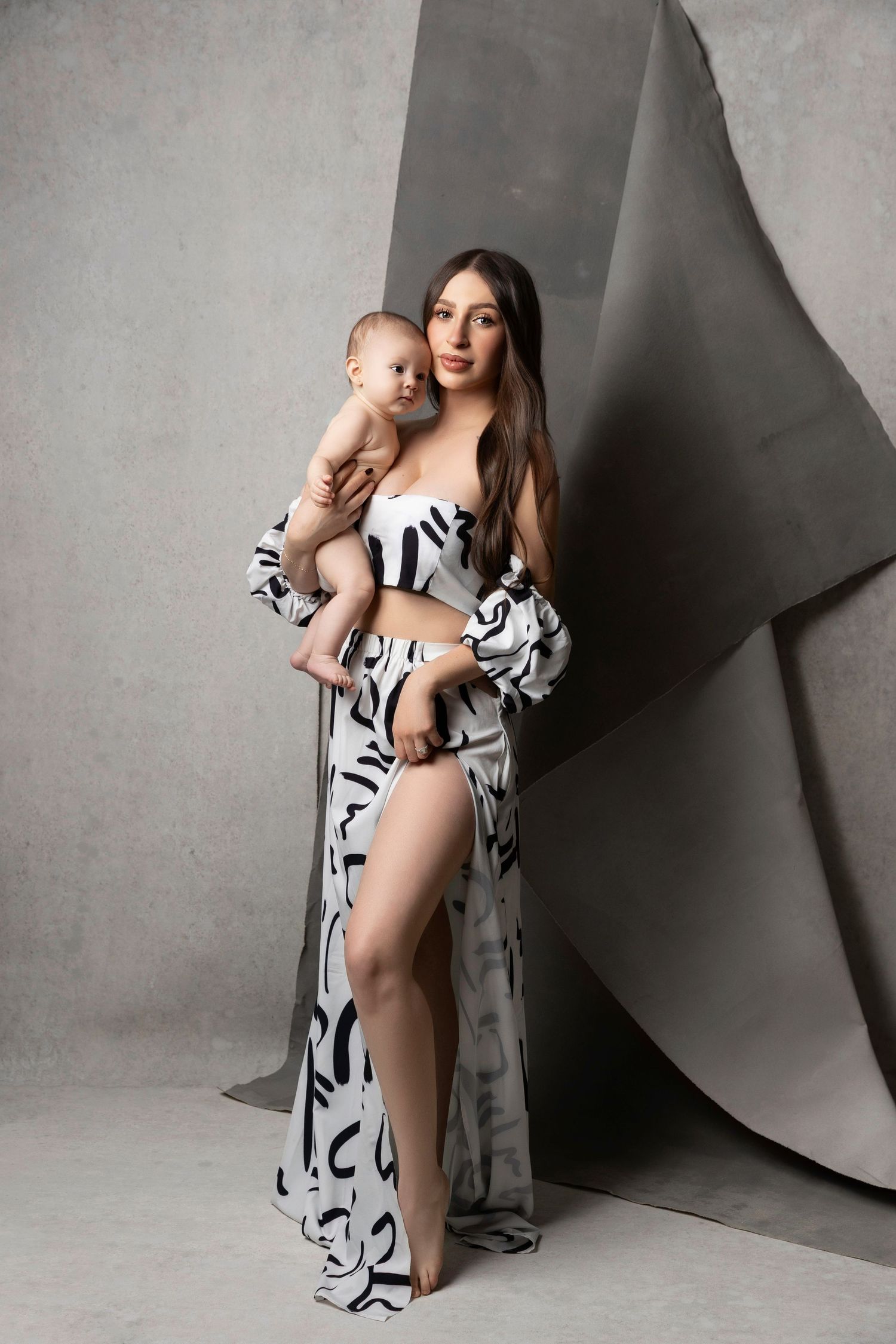 A series of artistic maternity photos showing a woman in a black and white patterned robe against a gray backdrop.