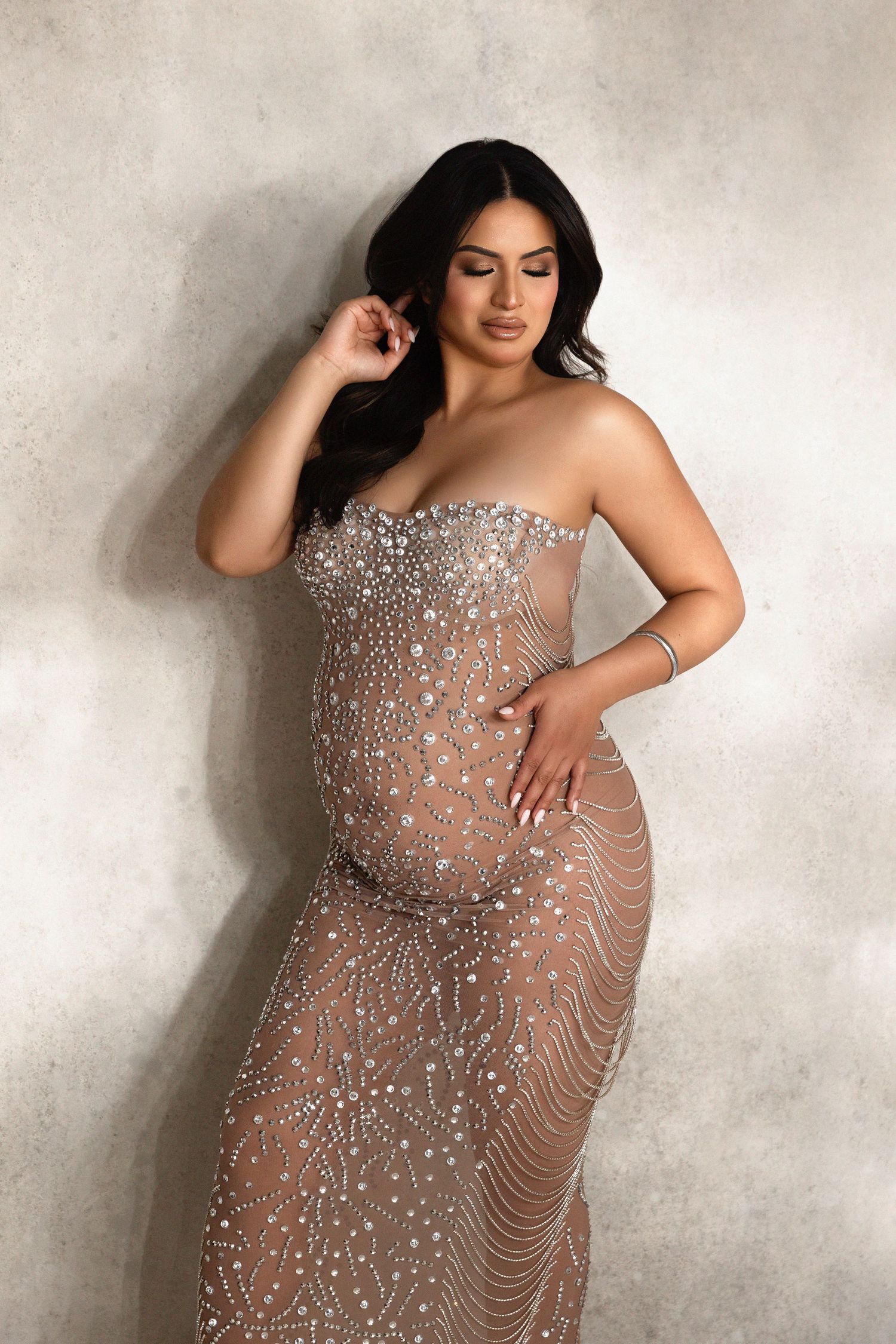 Maternity portraits in sparkly sheer gown against textured grey background.  Located in Palm Desert, California.