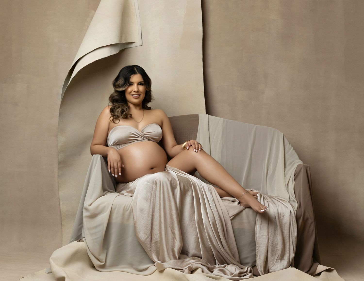 Dramatic maternity poses on beige fabric with soft studio lighting.  Located in Palm Desert, California.