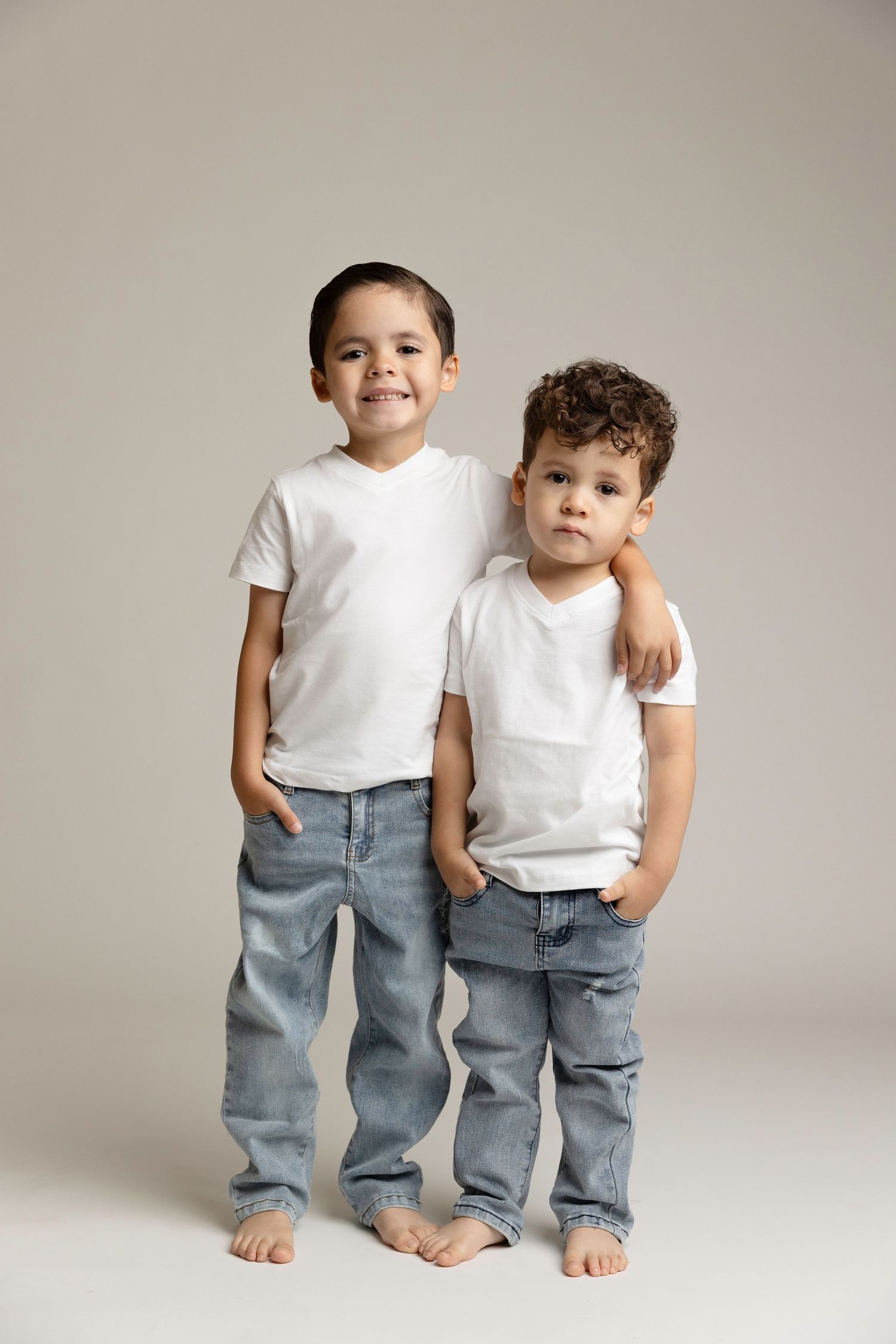 Two children in white t-shirts and jeans posing against neutral studio background.  Located in Palm Desert, California.