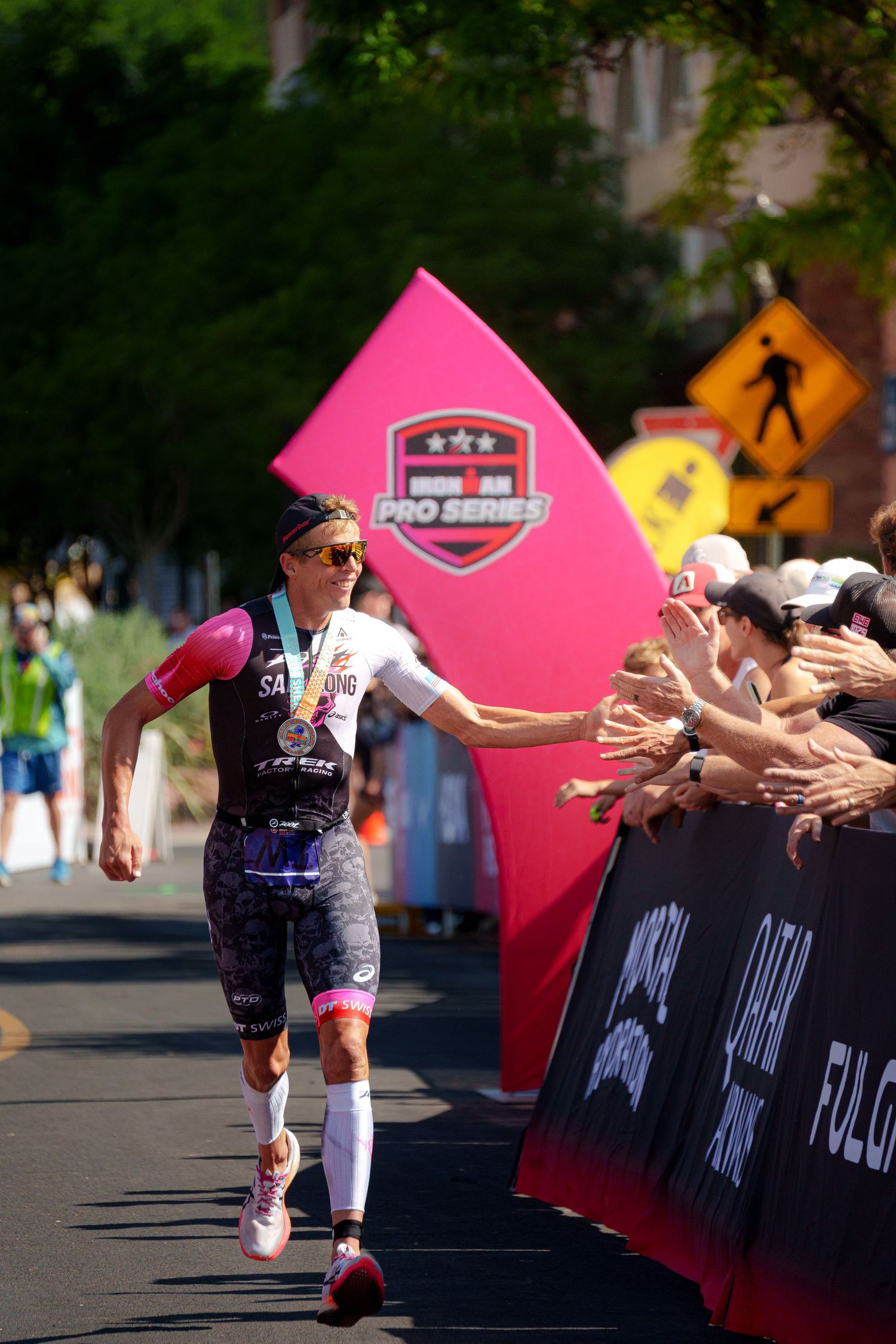 Pro triathlete Sam Long high-fives fans along the finish chute at an Ironman Pro Series event.