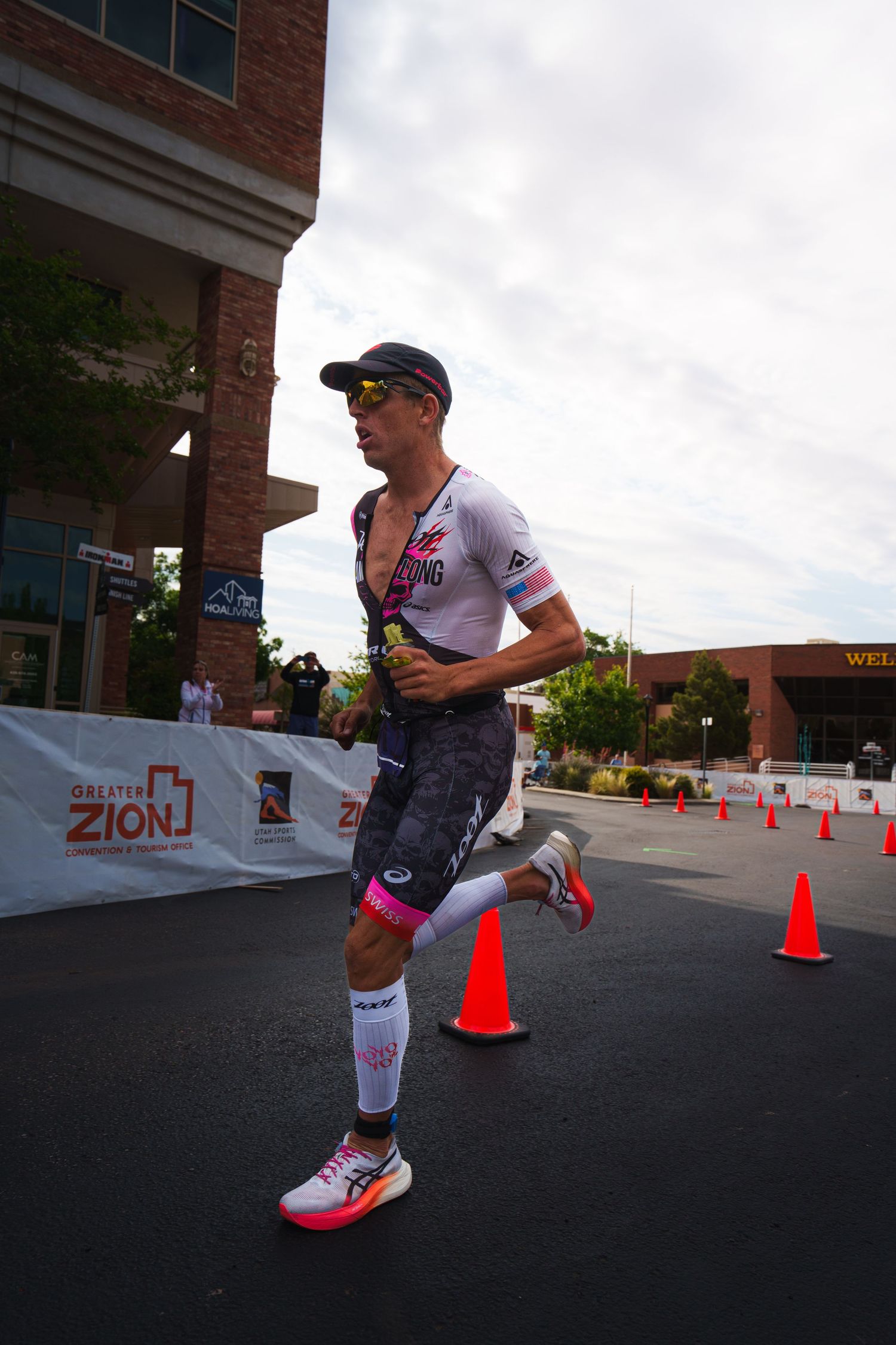 A triathlete runs past orange cones near the Greater Zion Convention center during an Ironman race.