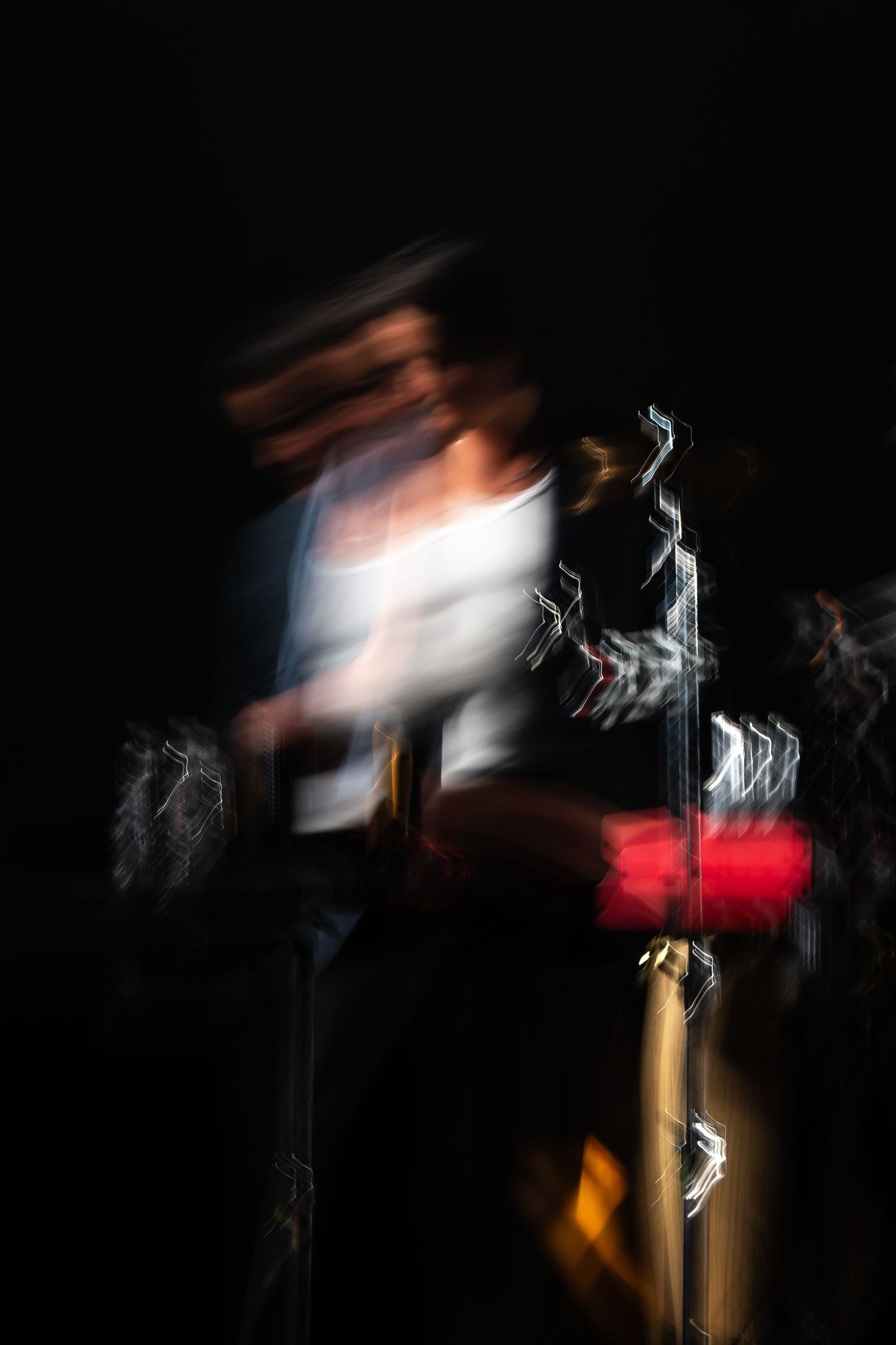 Abstract motion blur of a saxophone player performing on a dark stage with red and gold tones.
