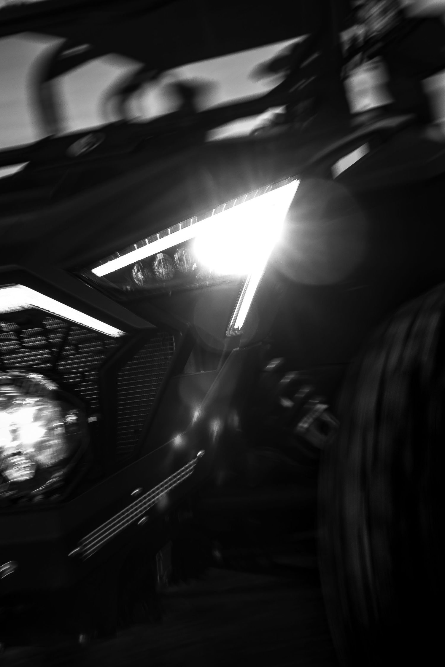 Close-up black and white photo of a UTV side-by-side vehicle headlight glowing brightly in the dark.