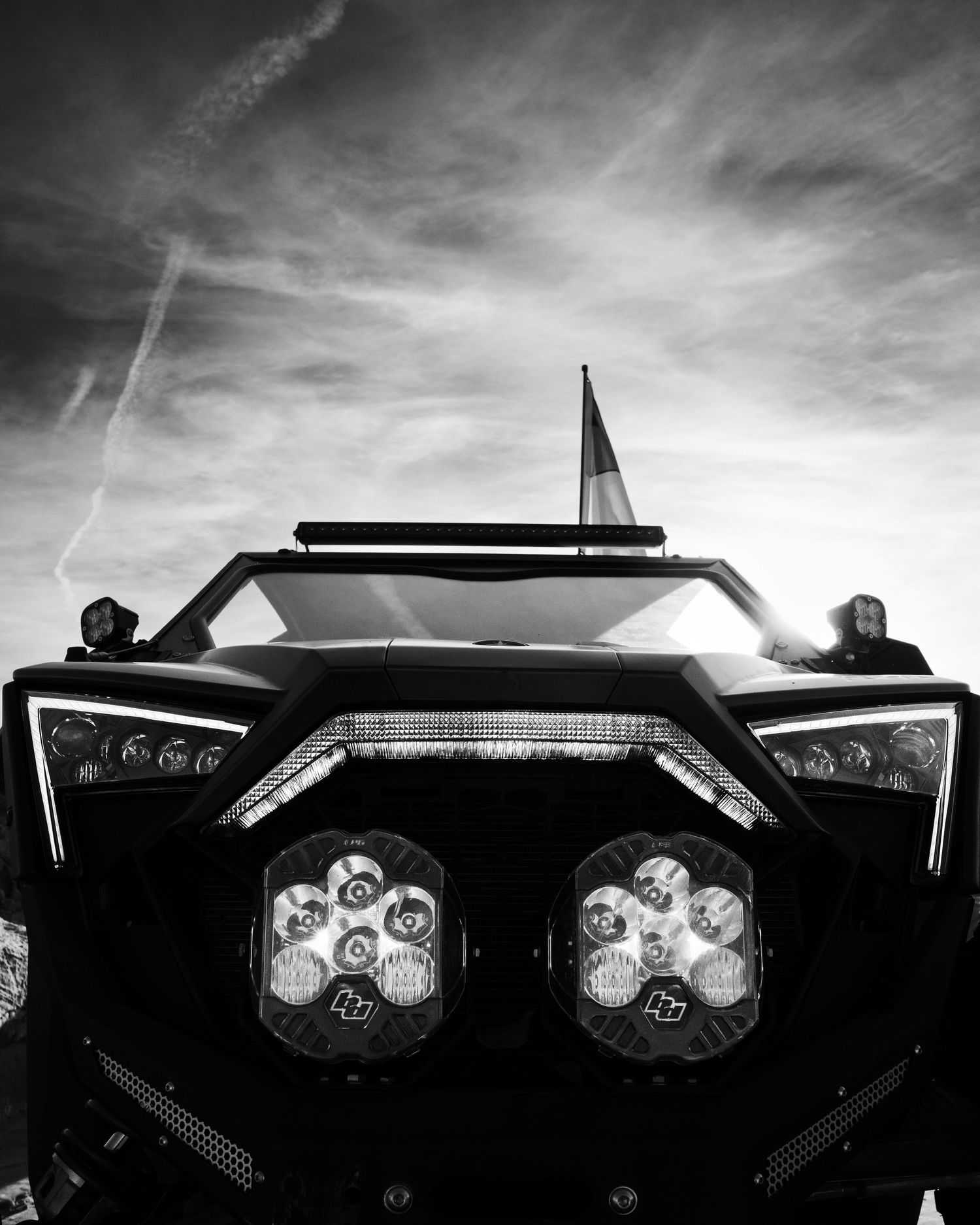Close-up front view of a UTV with dual LED lights in black and white against dramatic sky.