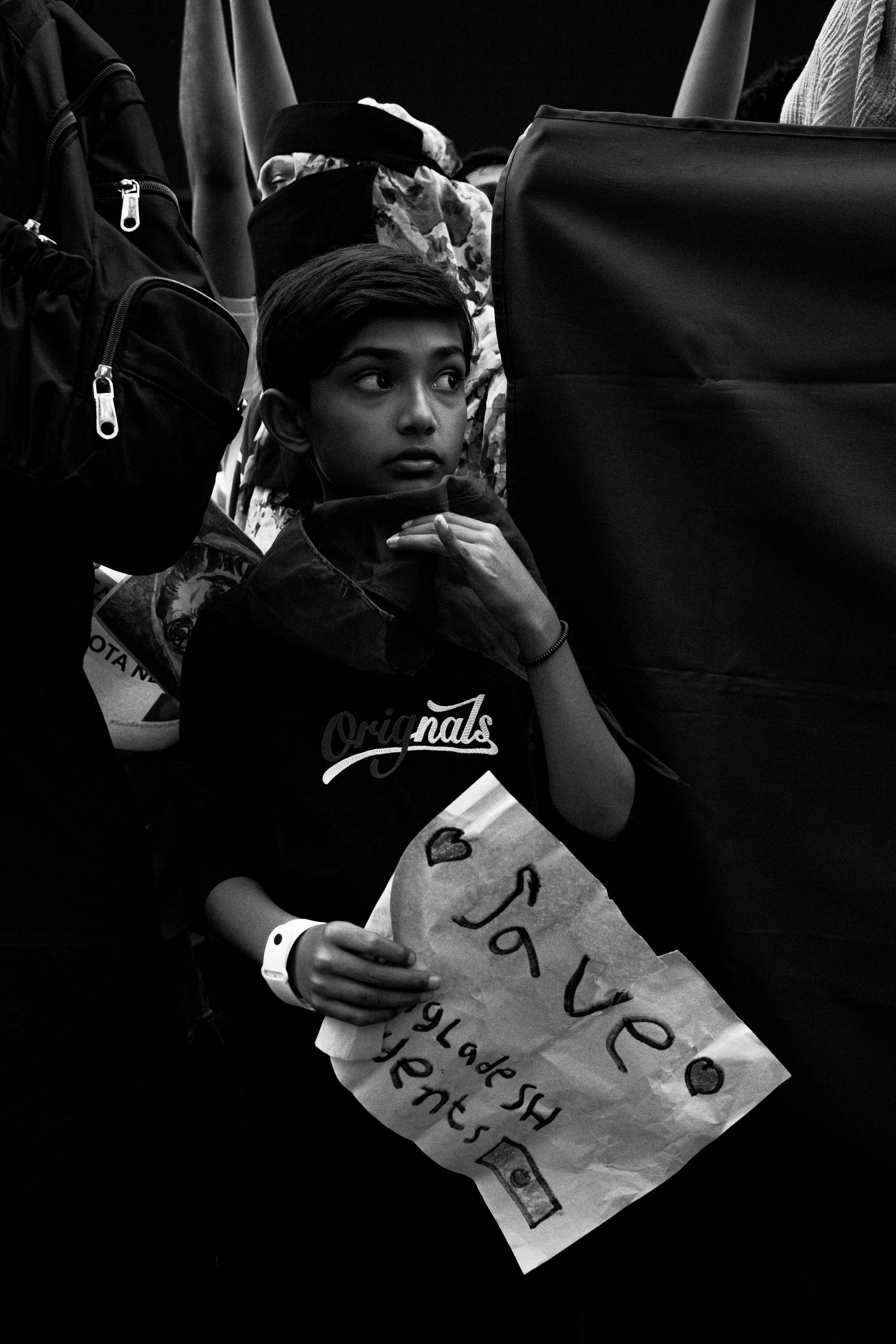Black and white portrait of a young boy holding a handwritten Save the Planet sign at a protest.