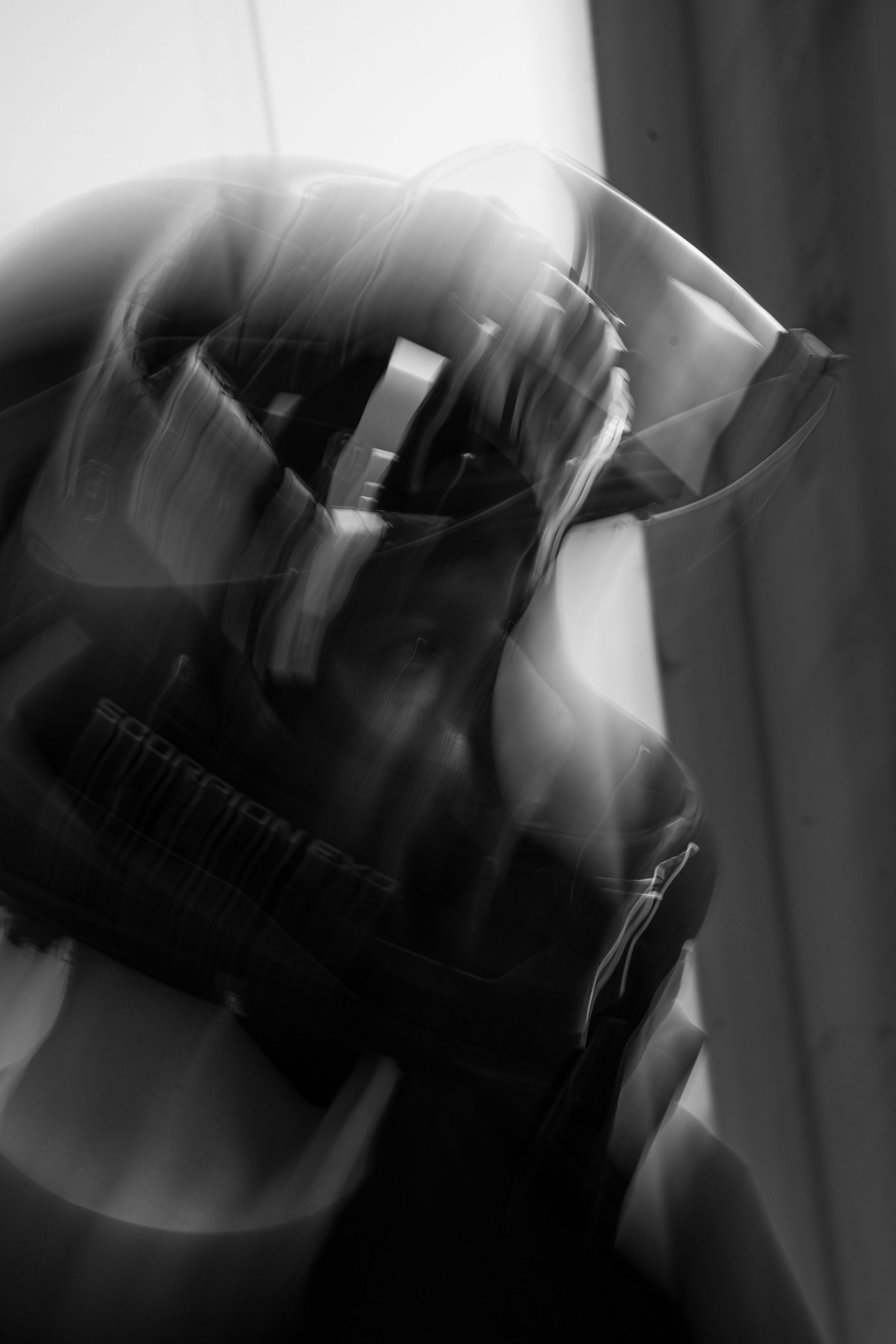 Close-up black and white abstract shot of motorcycle helmet visor with light reflections.