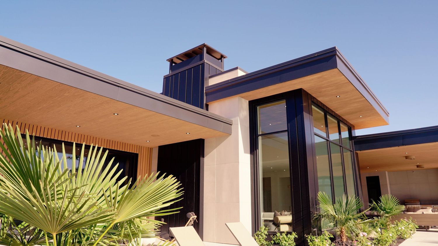 Contemporary desert home with flat roof, large windows, and tropical landscaping.