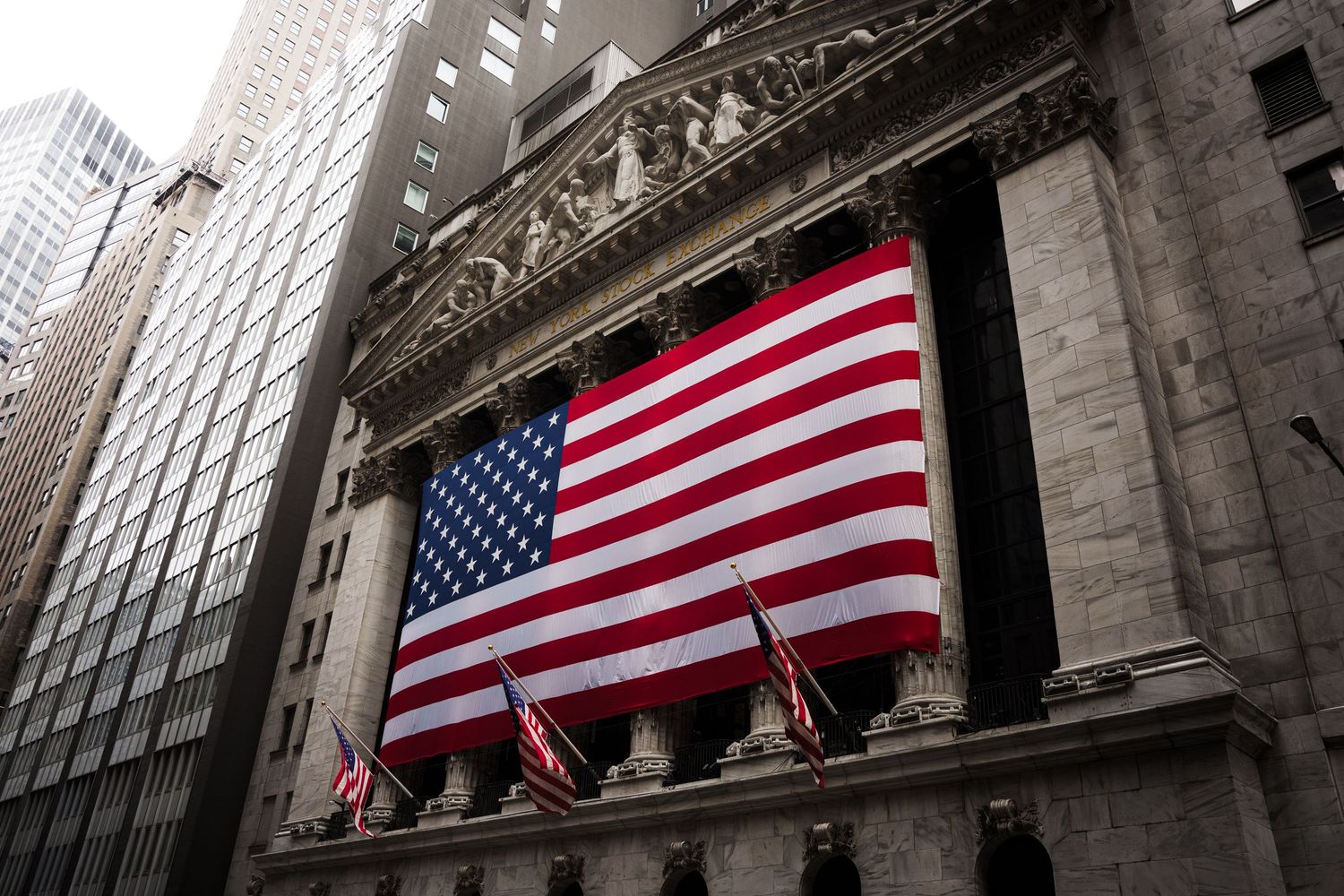 American flag draped on the neoclassical facade of the New York Stock Exchange on Wall Street.