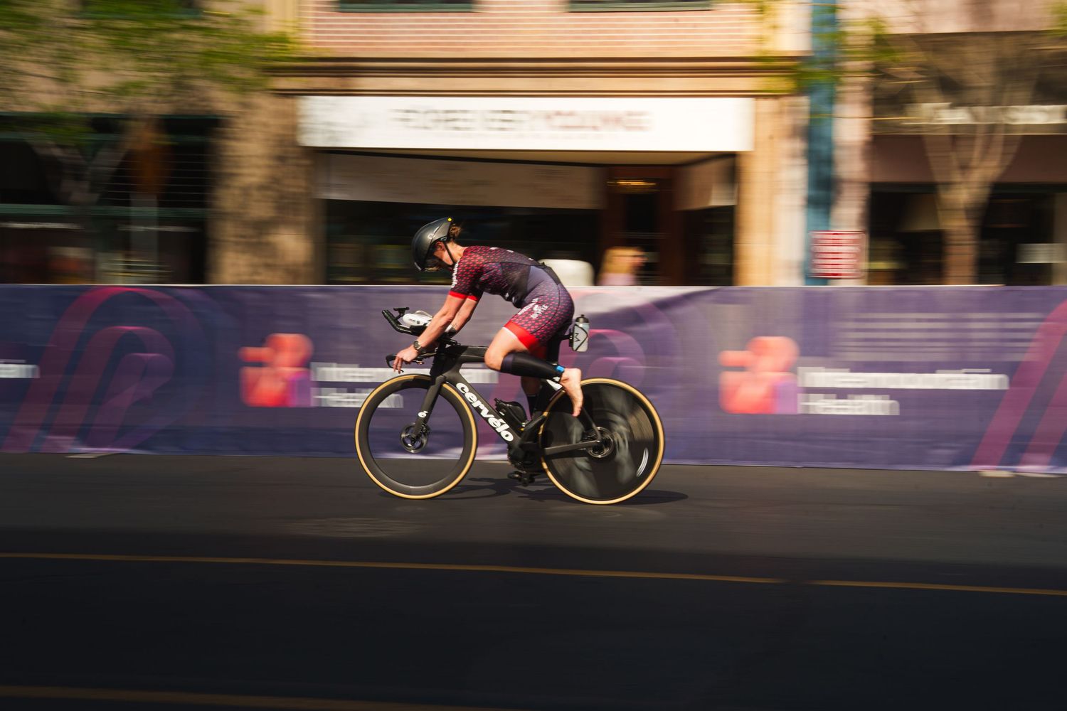 Motion-blurred photo of a cyclist speeding through city streets during an Ironman triathlon bike leg.