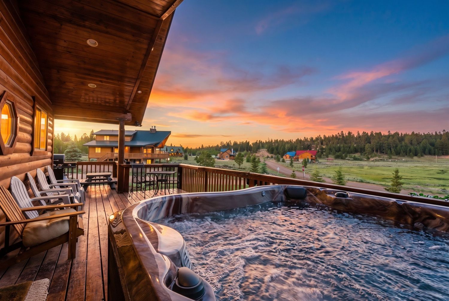 Log cabin deck with bubbling hot tub overlooking scenic meadow at stunning golden sunset.