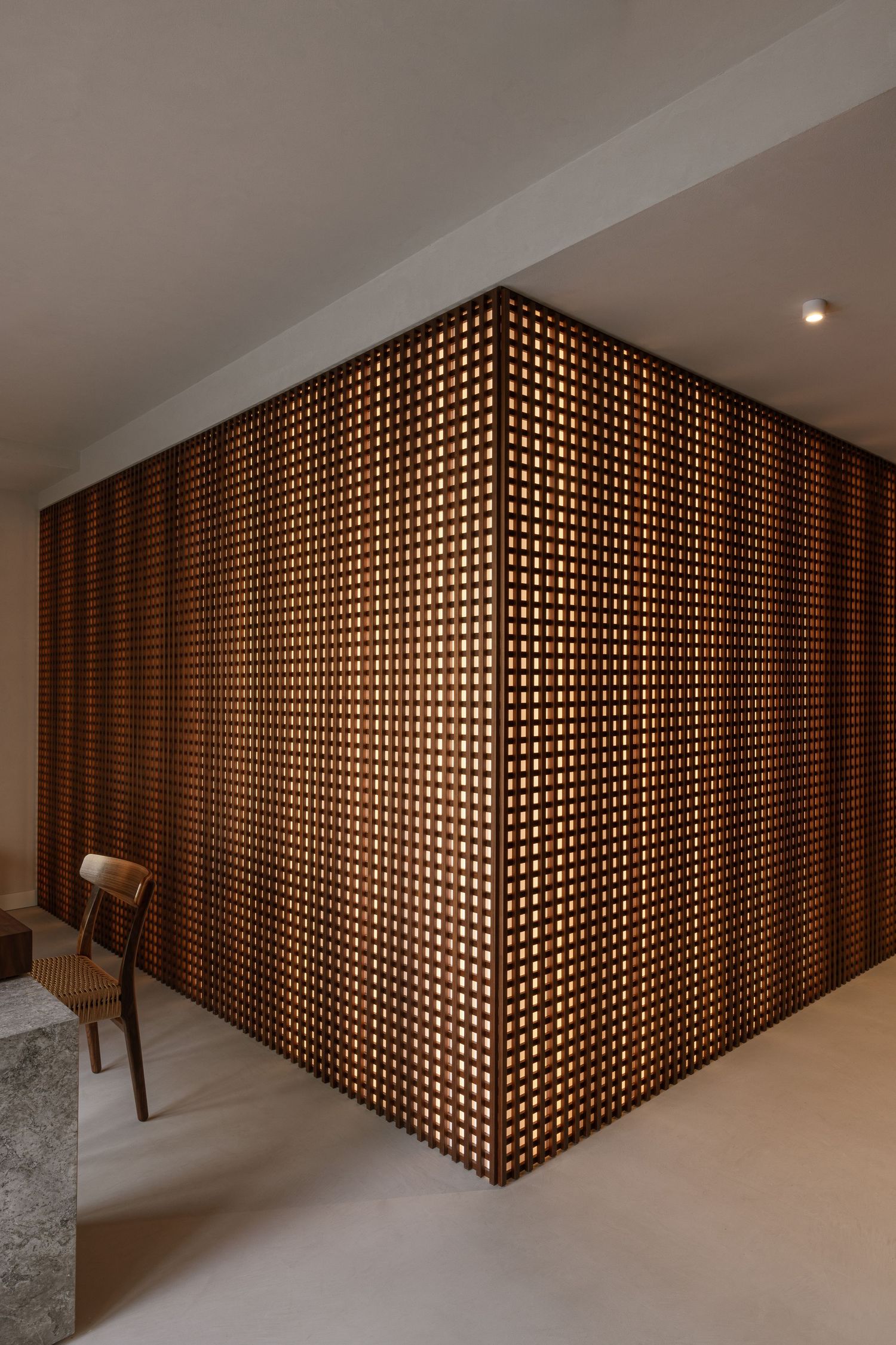 Modern interior space featuring a geometric wooden lattice wall partition with diagonal pattern and clean white floors by Studio Fluid.
