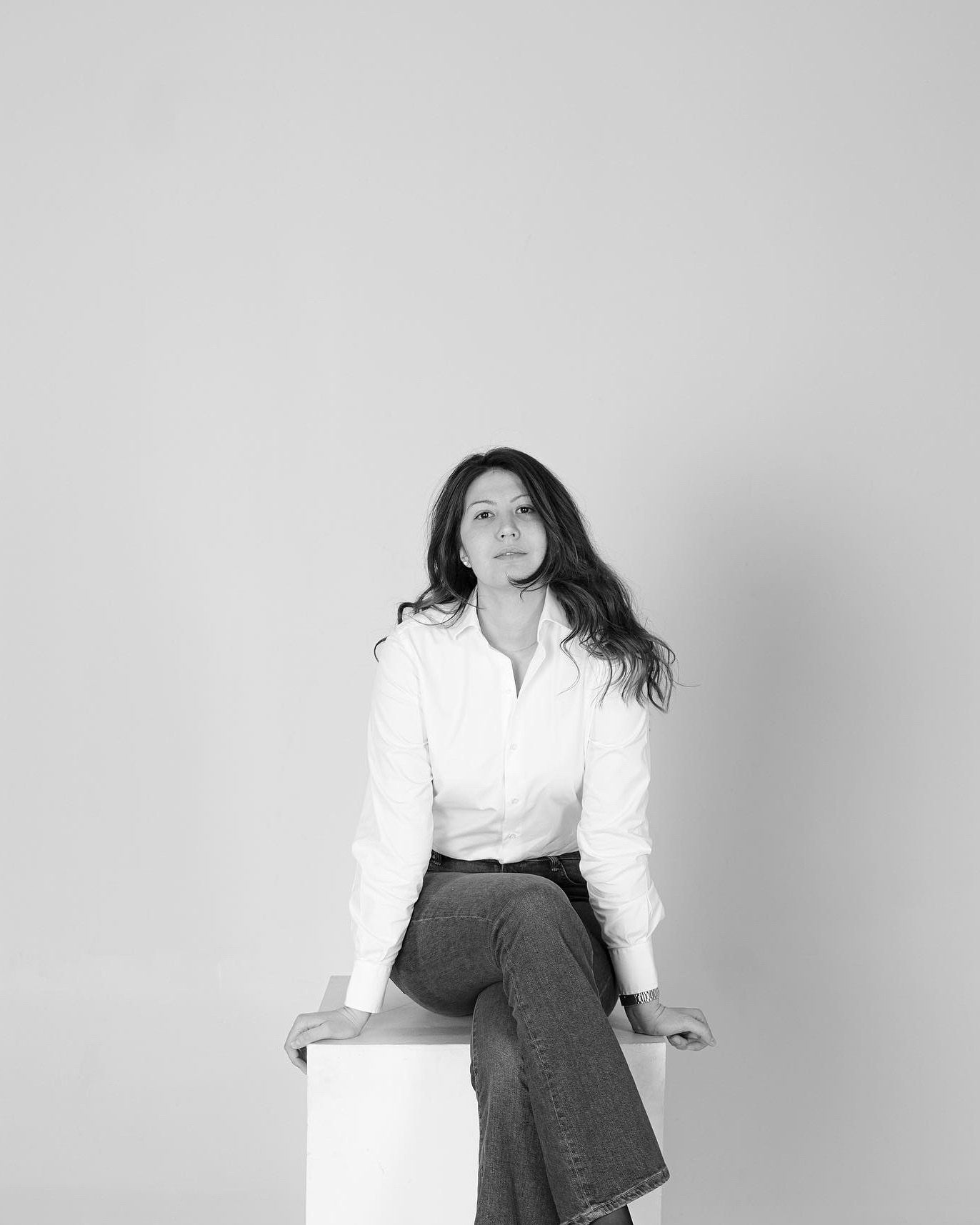 Photographer's portrait.Black and white studio portraits showing a figure in a white blouse and gray skirt posing against a light backdrop.