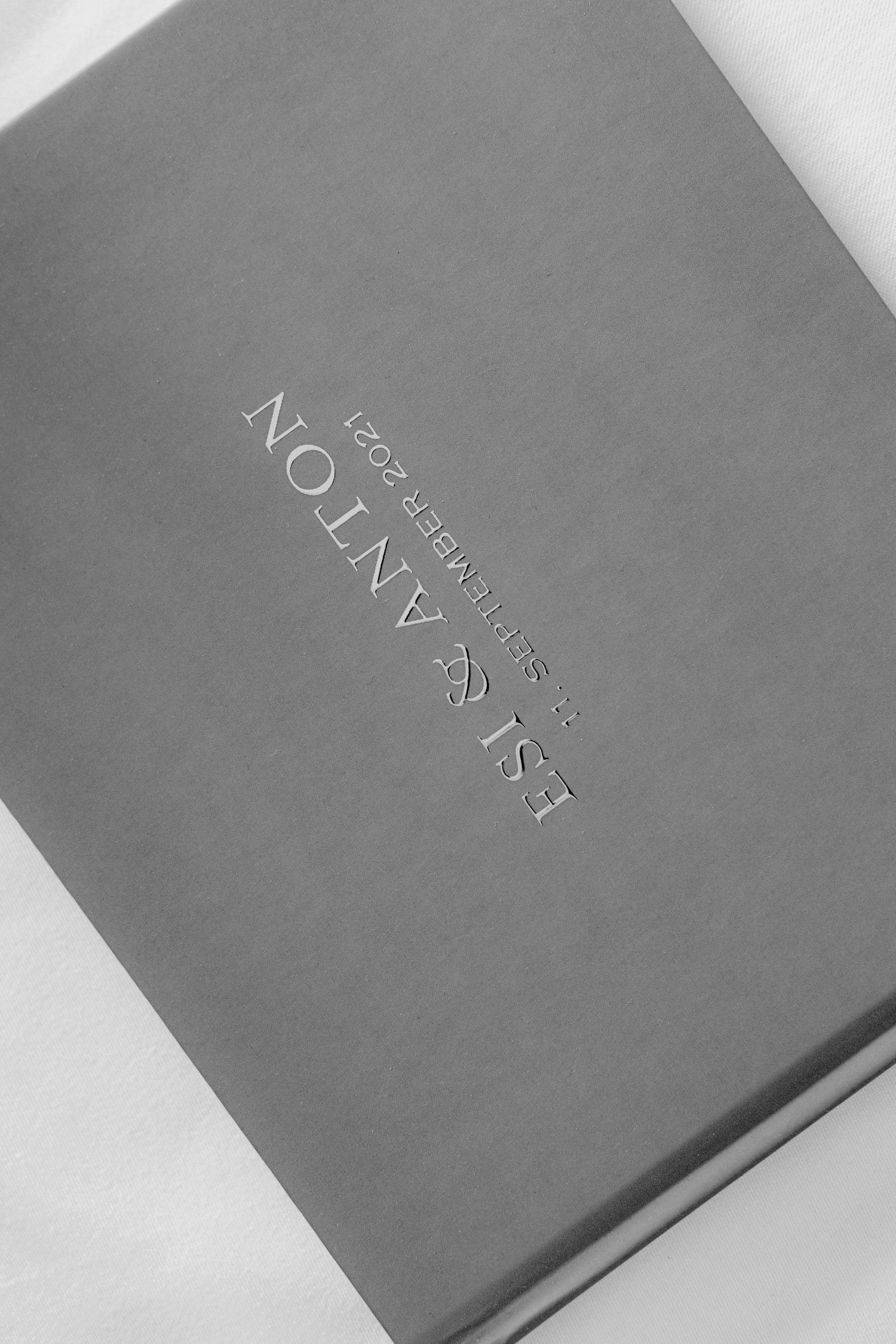 Gray hardcover books with embossed text shown from different angles on a light background.