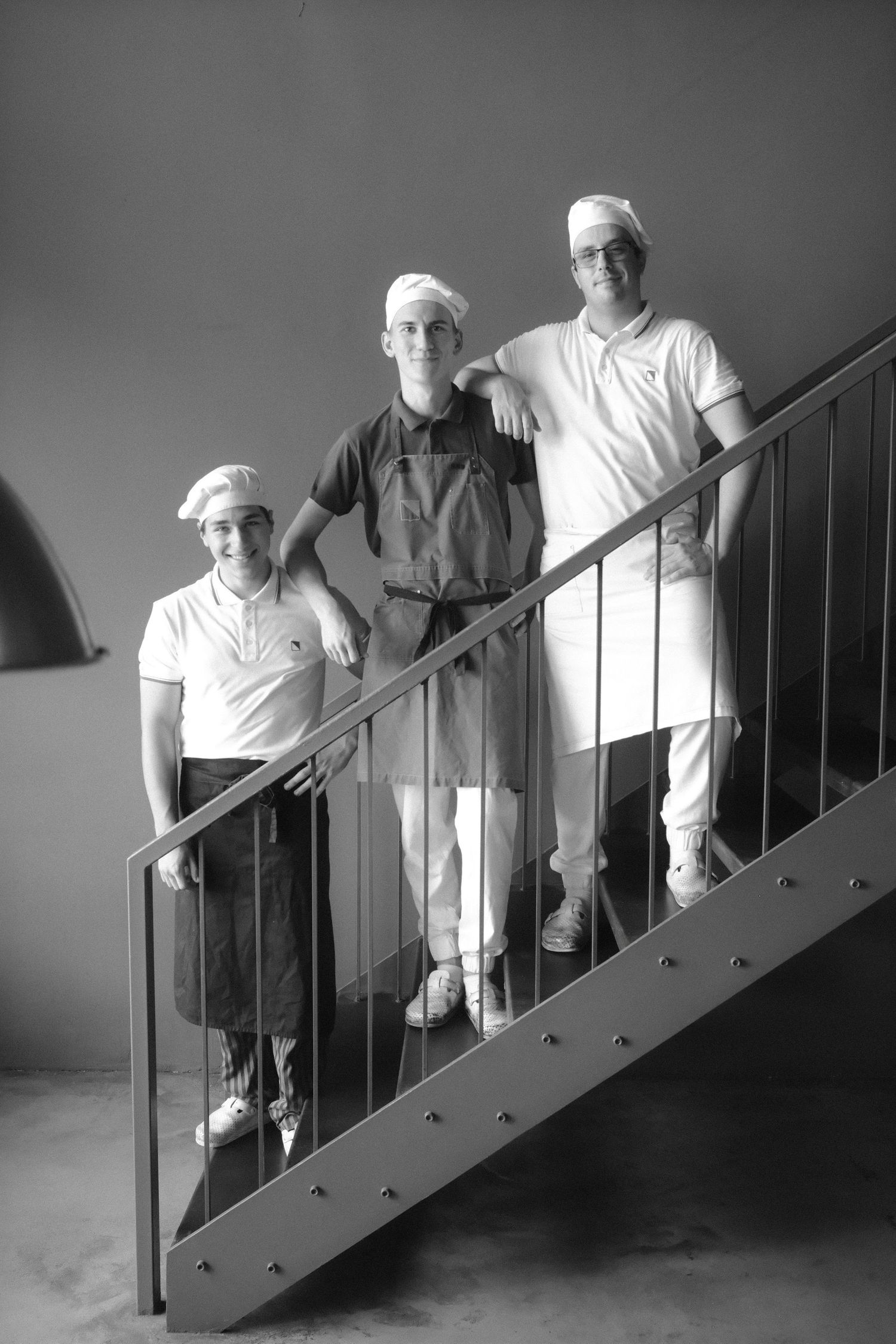 Black and white sequence of three people descending a staircase in white shirts, creating a dynamic visual pattern.