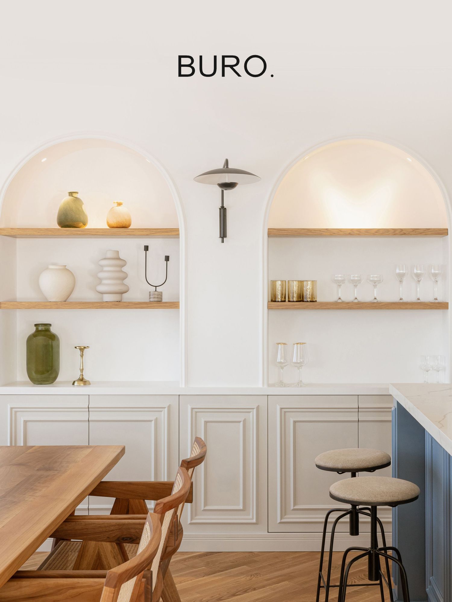 Modern minimalist restaurant interior with wooden tables, arched walls, and floating shelves displaying decorative items.