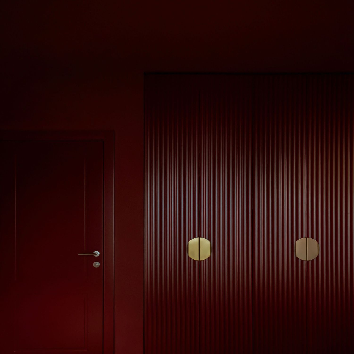 Burgundy colour bedroom with a minimalist closet with golden brass handles by Studio Fluid.
