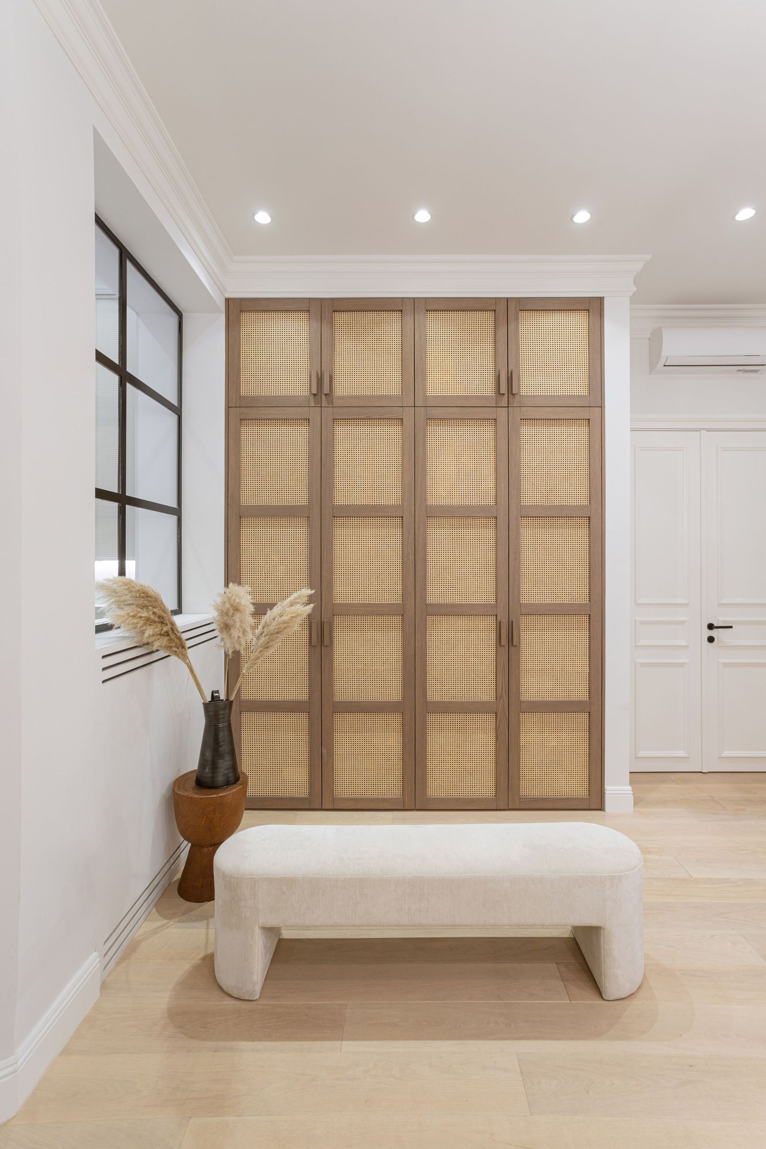 Interior with light wood floors and built-in cabinets featuring rattan paneling in a minimalist design by Dello Studio, Stasa Radmilovic.