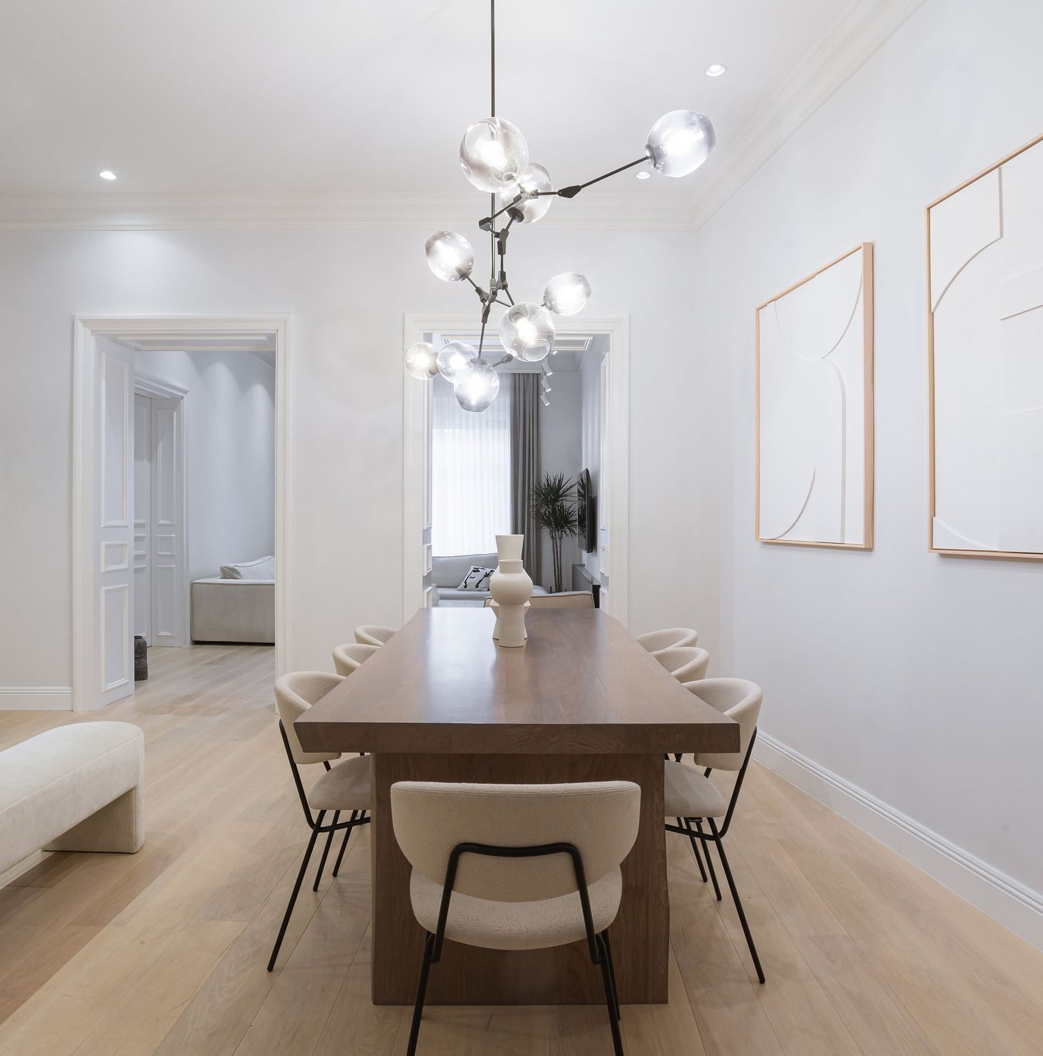 Bright room interior with wooden table, beige chairs, and hardwood flooring in an open concept space by Stasa Radmilovic, Dello Studio