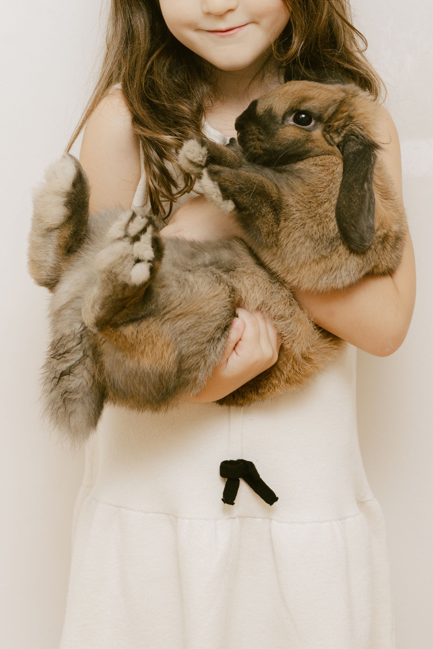 A series of sepia-toned photos showing someone in a white dress holding and cuddling with a fluffy brown cat.