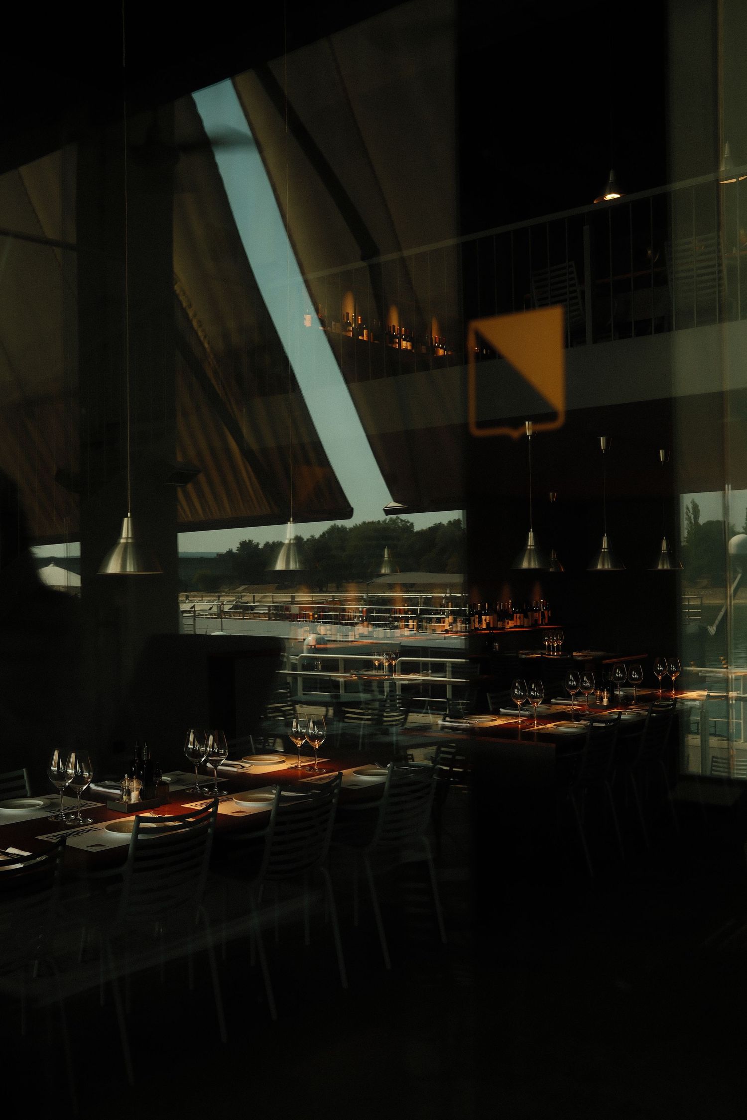 Interior view of a dimly lit modern restaurant with angular architectural features and sleek table settings.