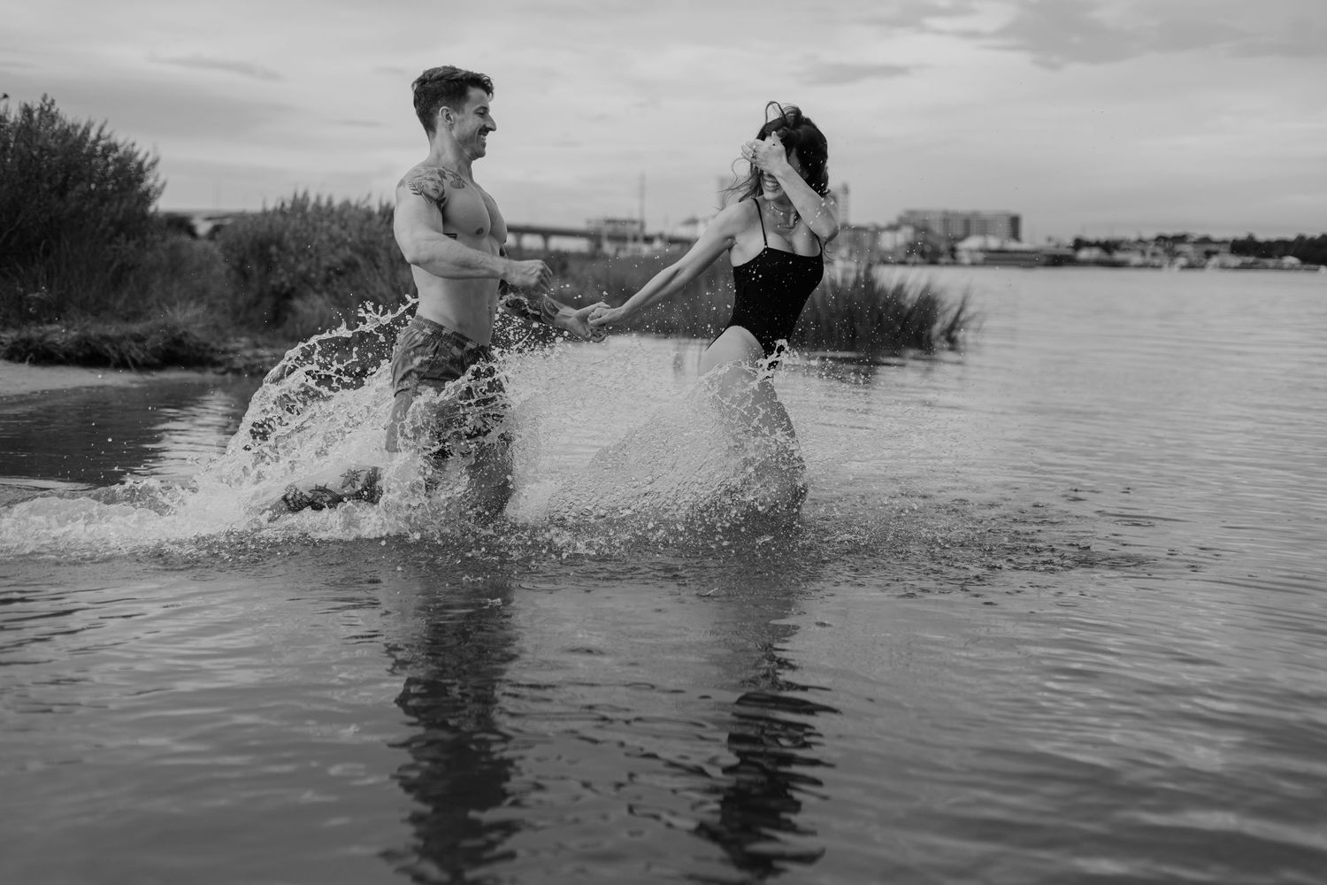 A sequence of black and white photos showing a couple splashing and playing together in a lake during summertime.
