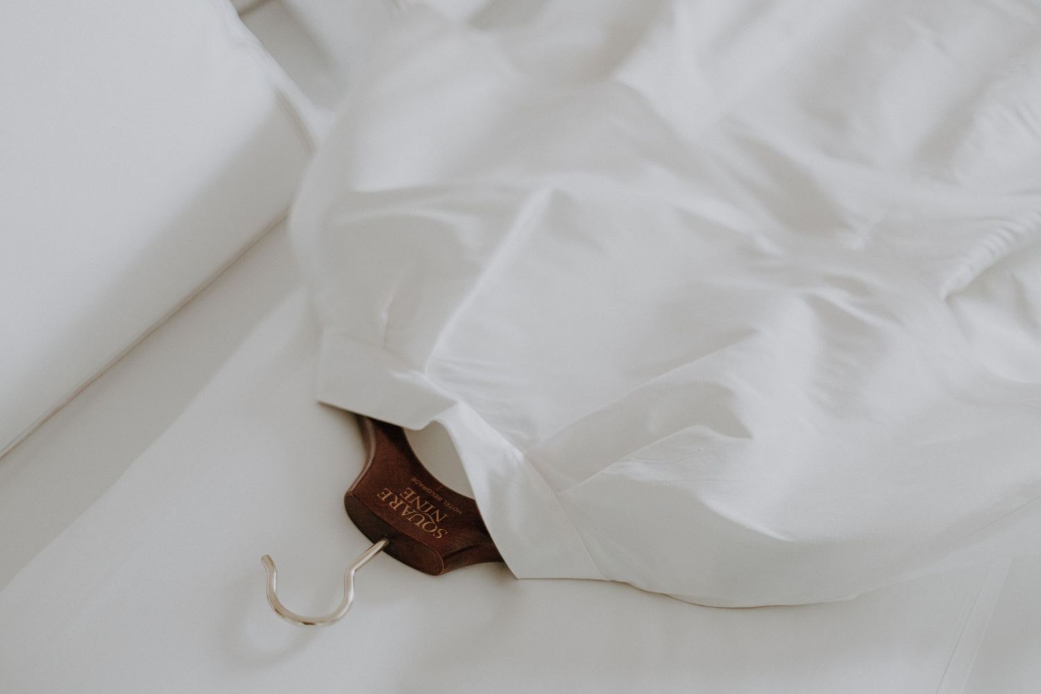 White crumpled fabric or textile material creates soft folds and shadows against a light background.