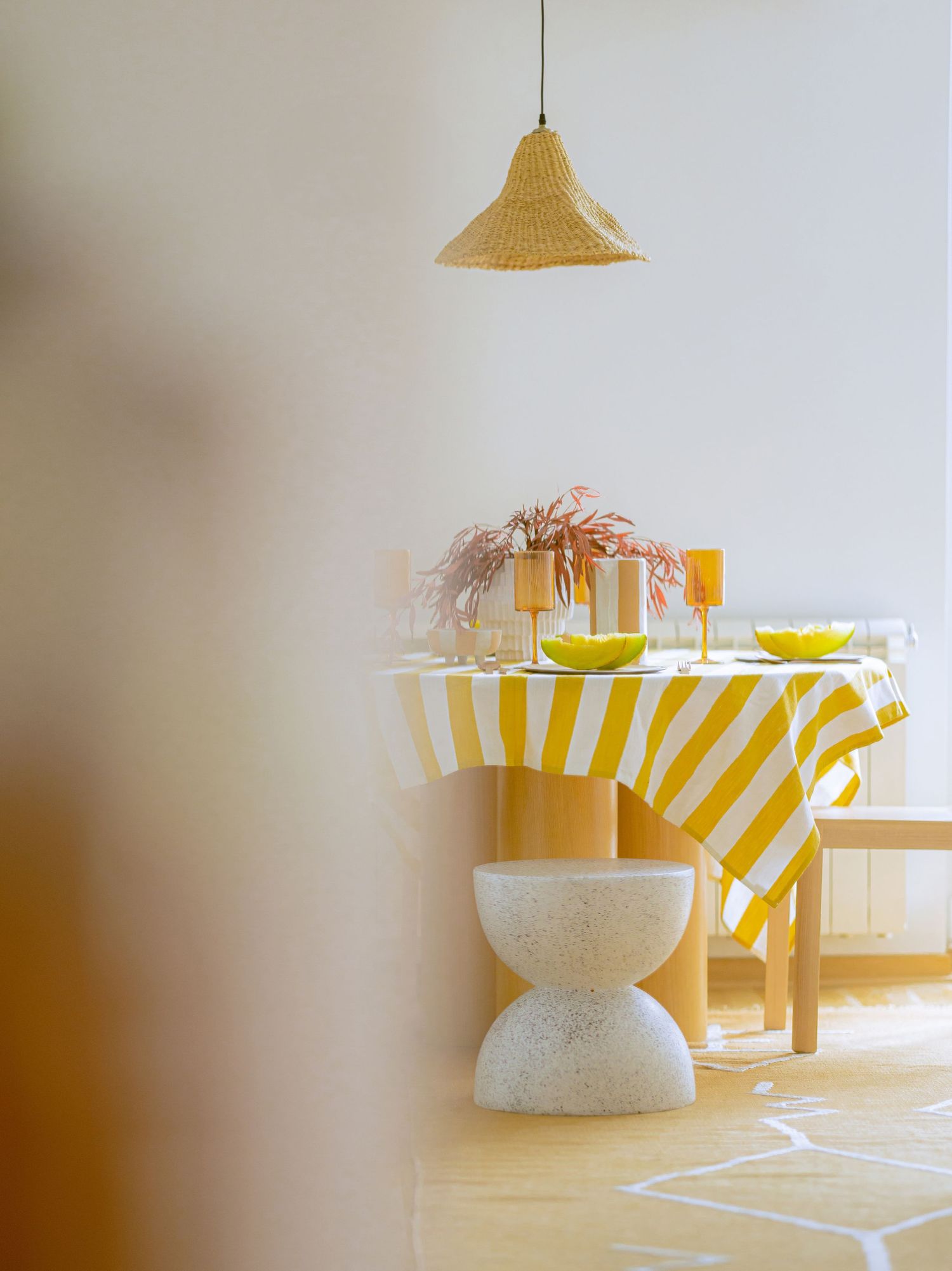 A series of yellow and white striped pendant lamps casting warm light in a minimalist interior space by Maja Interiors.