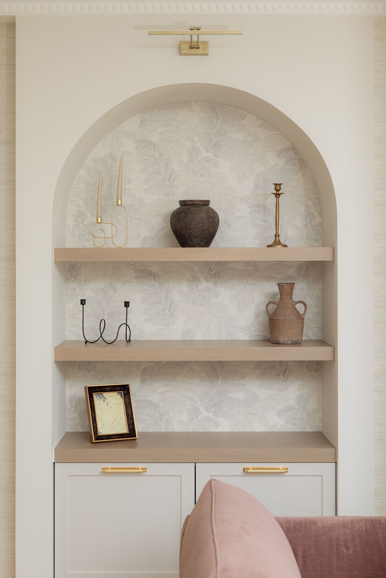 Built-in arched wall shelves with decorative vases and candlesticks in a modern neutral-toned living room by Vedrana Markovic.