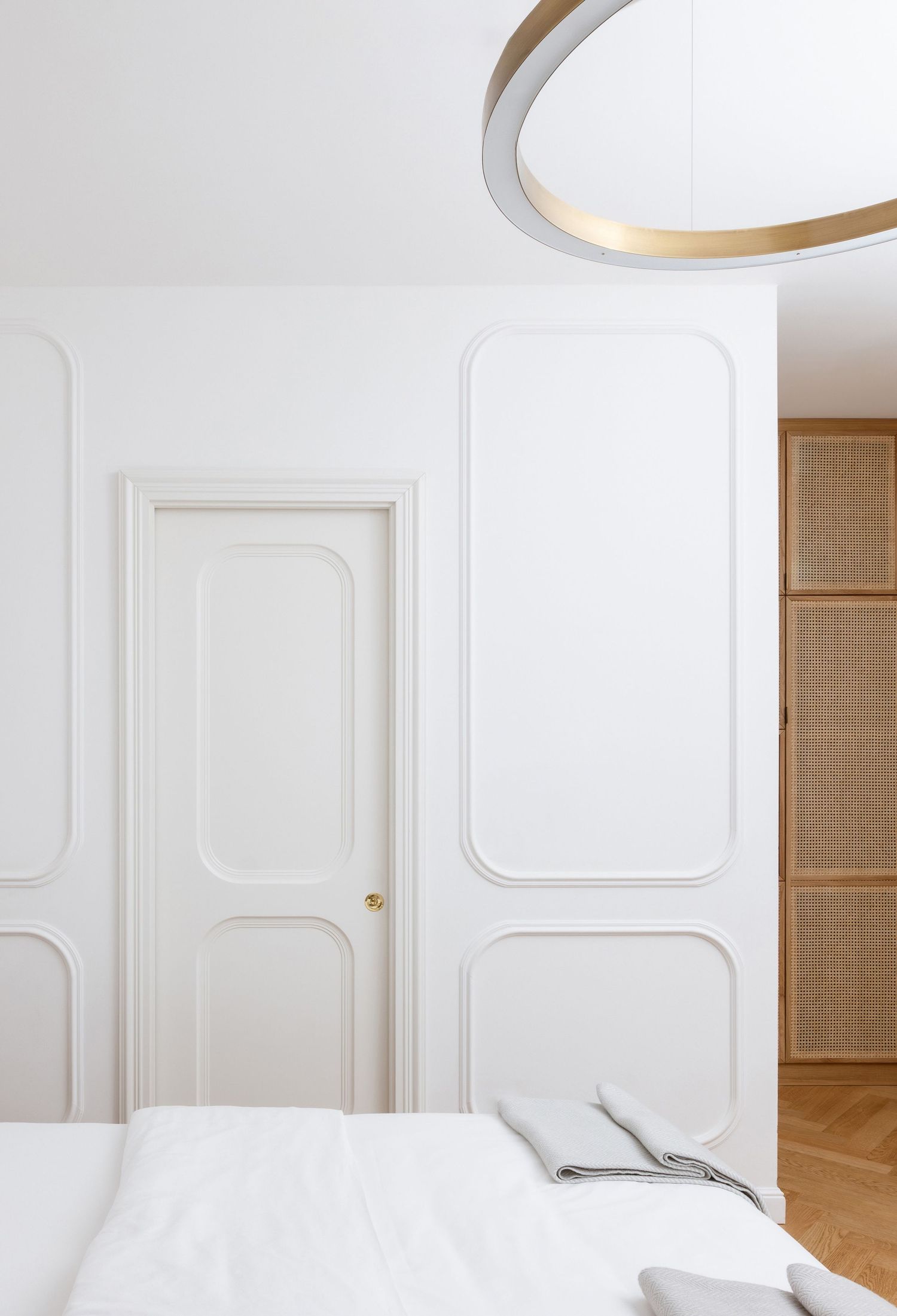 Modern white bedroom interior with minimalist decor, circular pendant lights, and paneled walls.