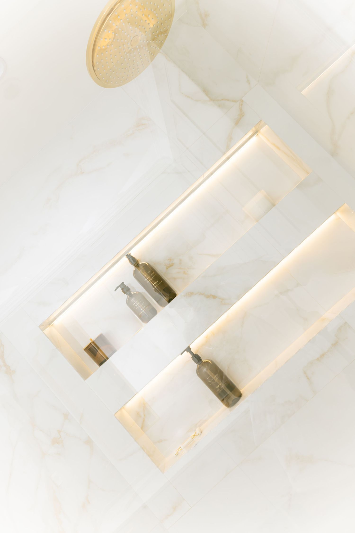Two glass vials with metal caps rest on a white marble surface in soft lighting.