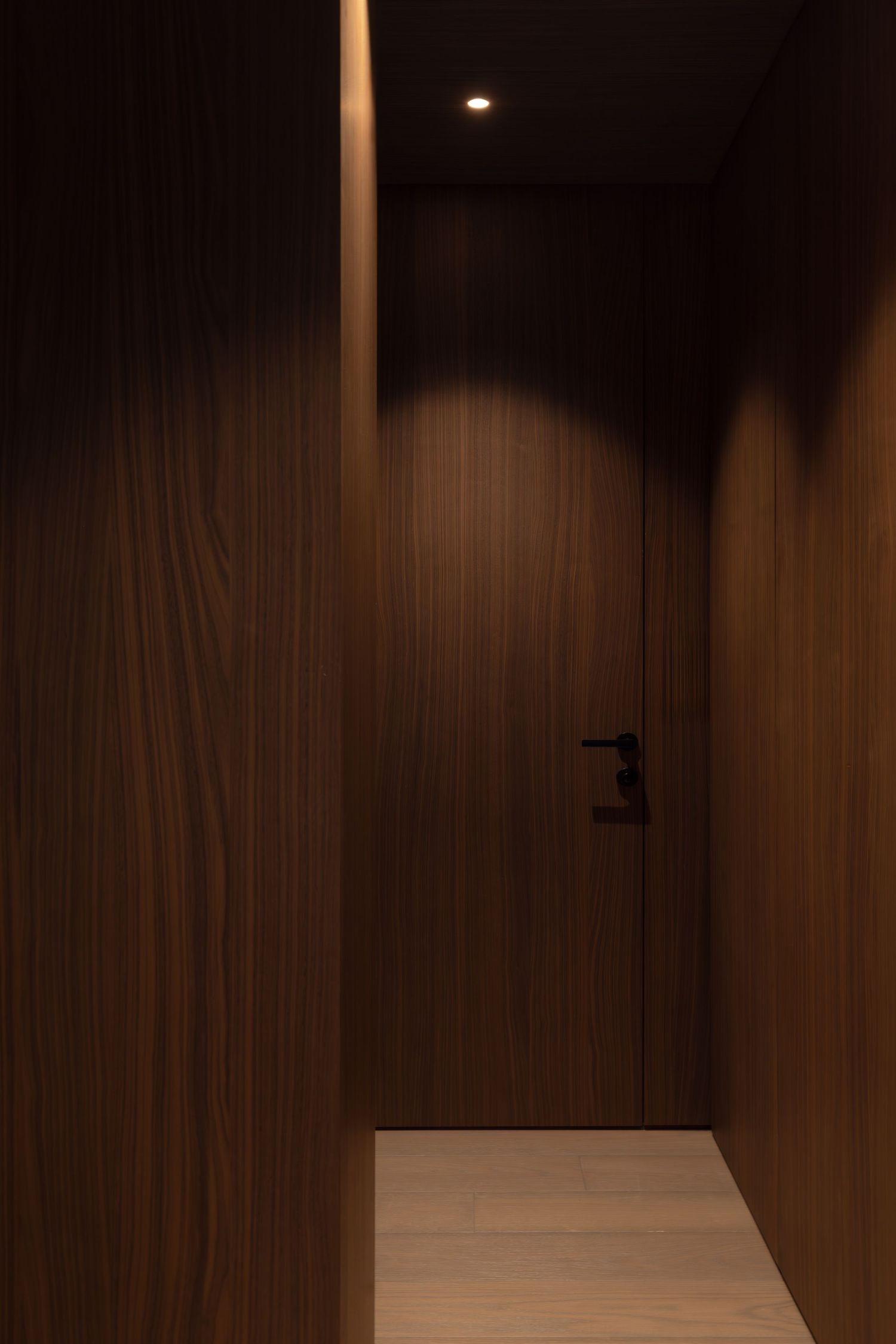 Modern dark wood paneled walls with recessed lighting create an elegant and minimalist interior space Studio Fluid.