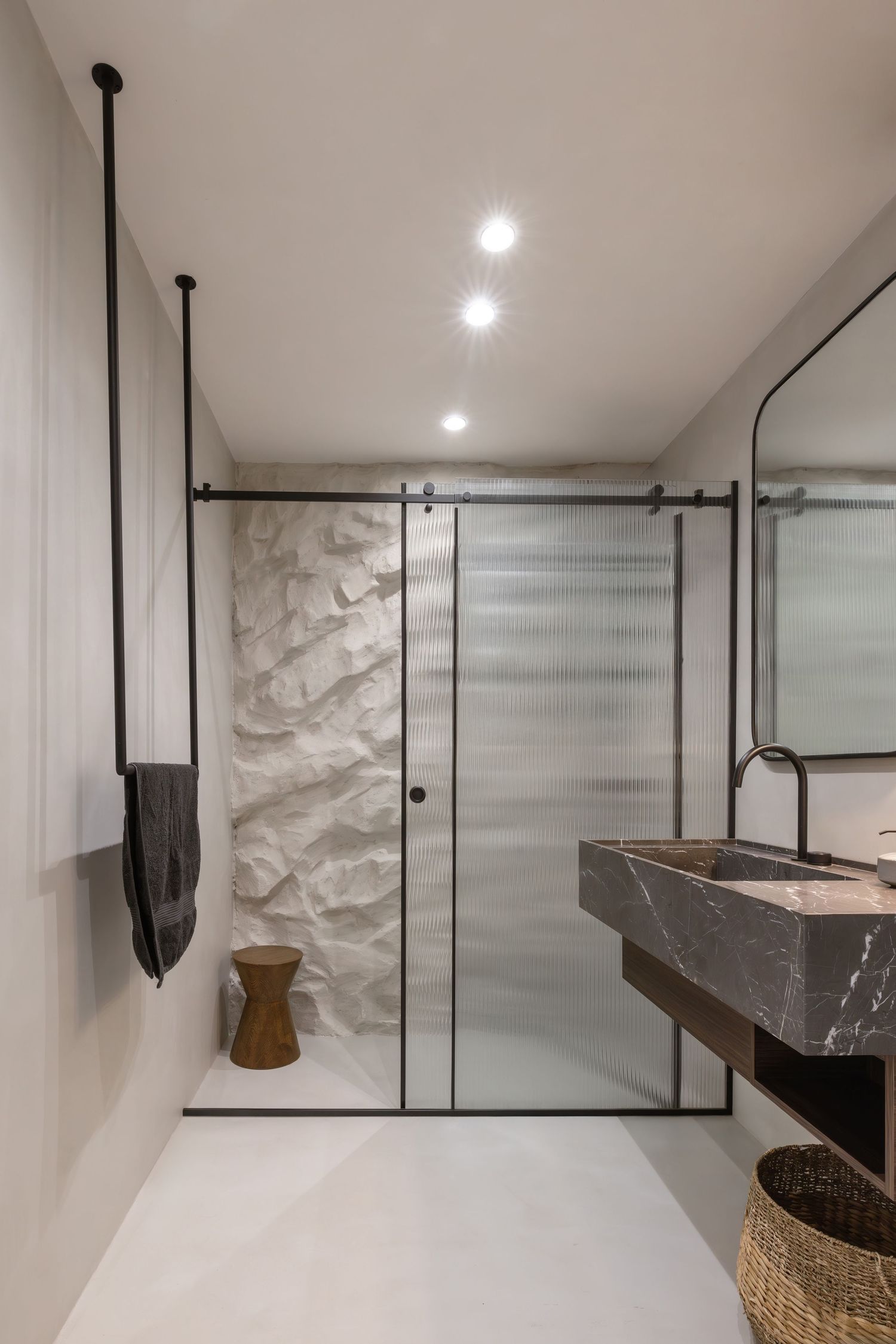 Modern bathroom design featuring a floating marble vanity with black hardware and pendant lighting against textured walls by WDA Architects.