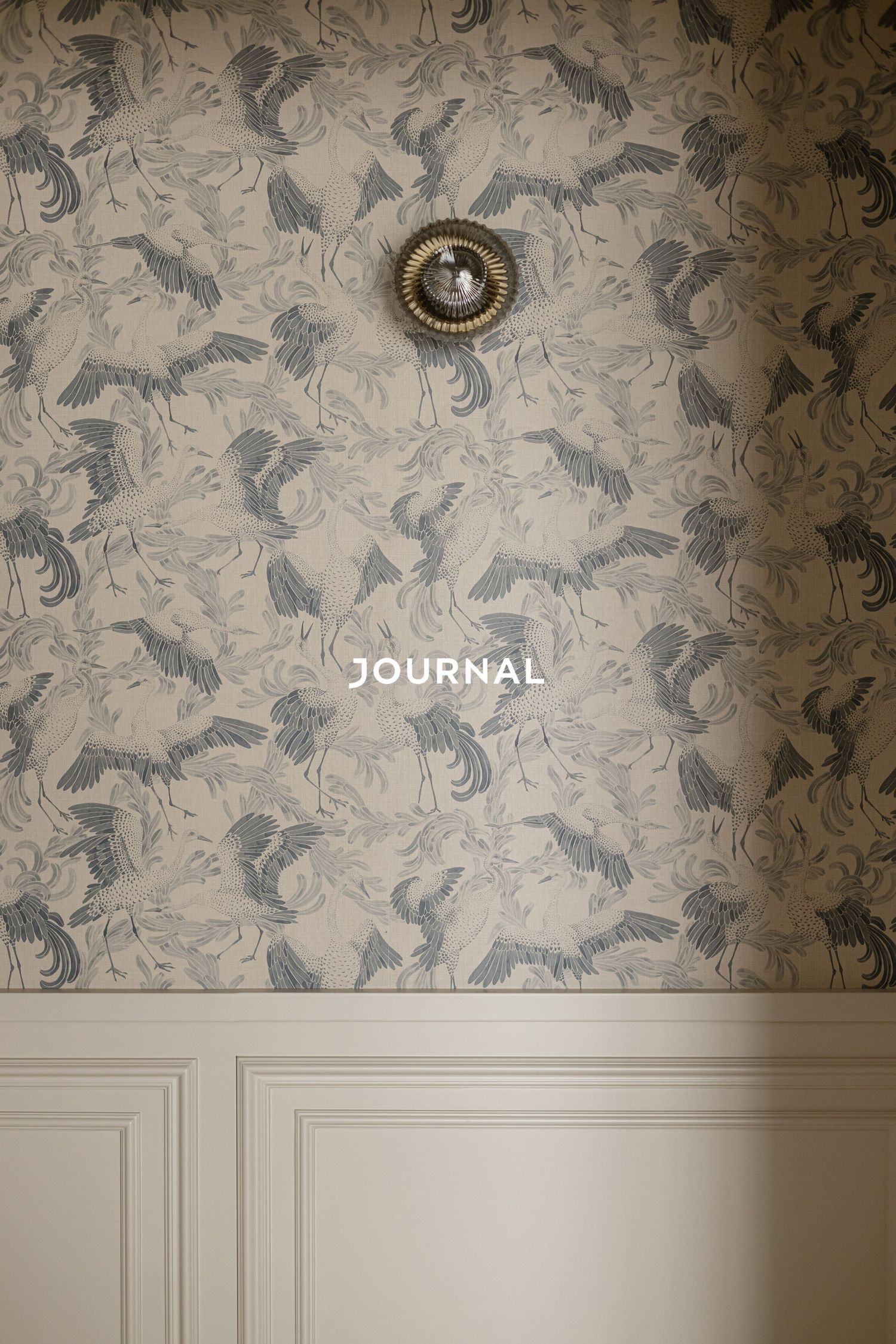 Elegant wallpaper with gray bird pattern and white wainscoting beneath a vintage ceiling light fixture.